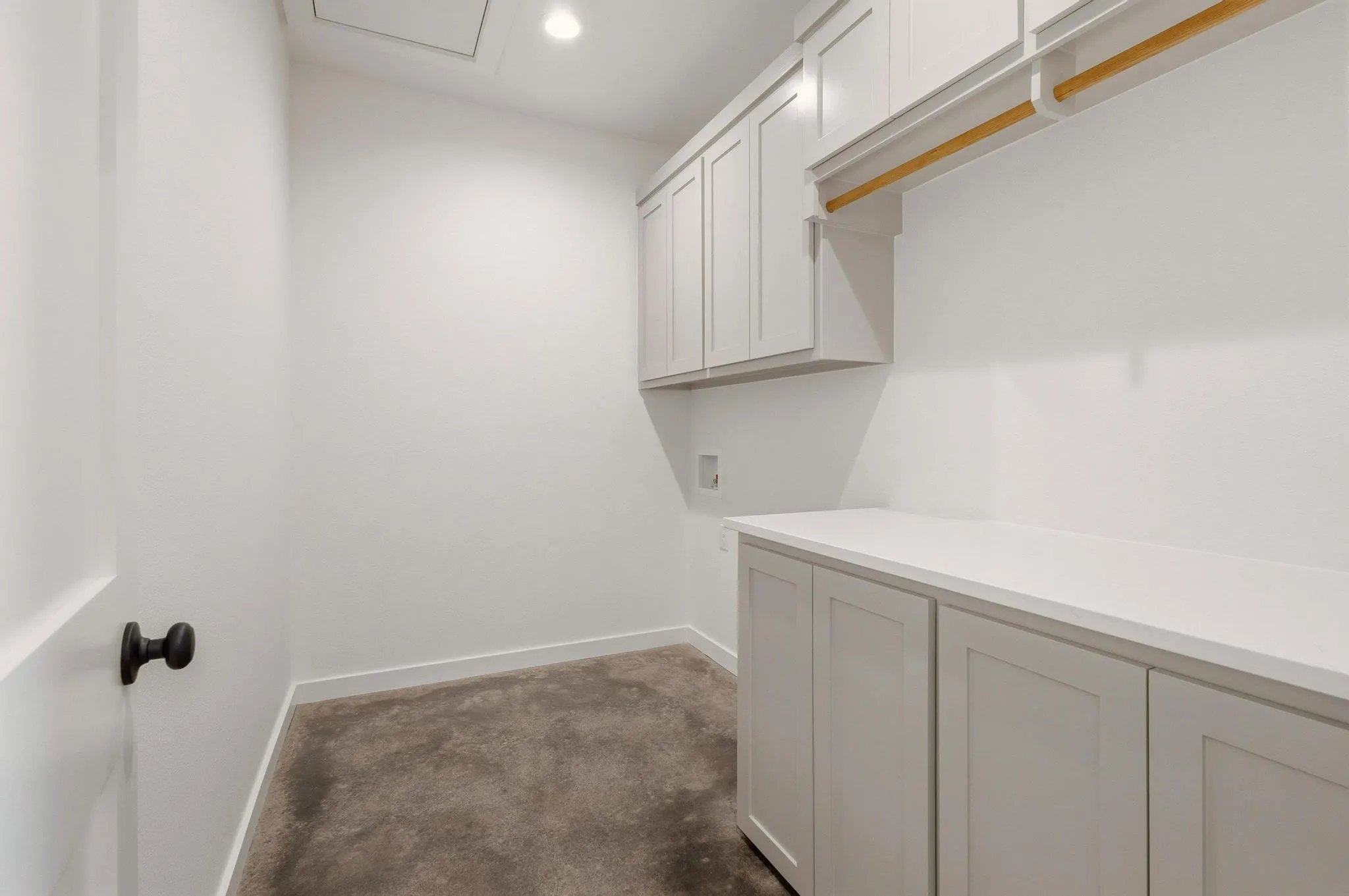 Utility room featuring white shaker-style cabinetry, a built-in hanging rod, and a spacious countertop