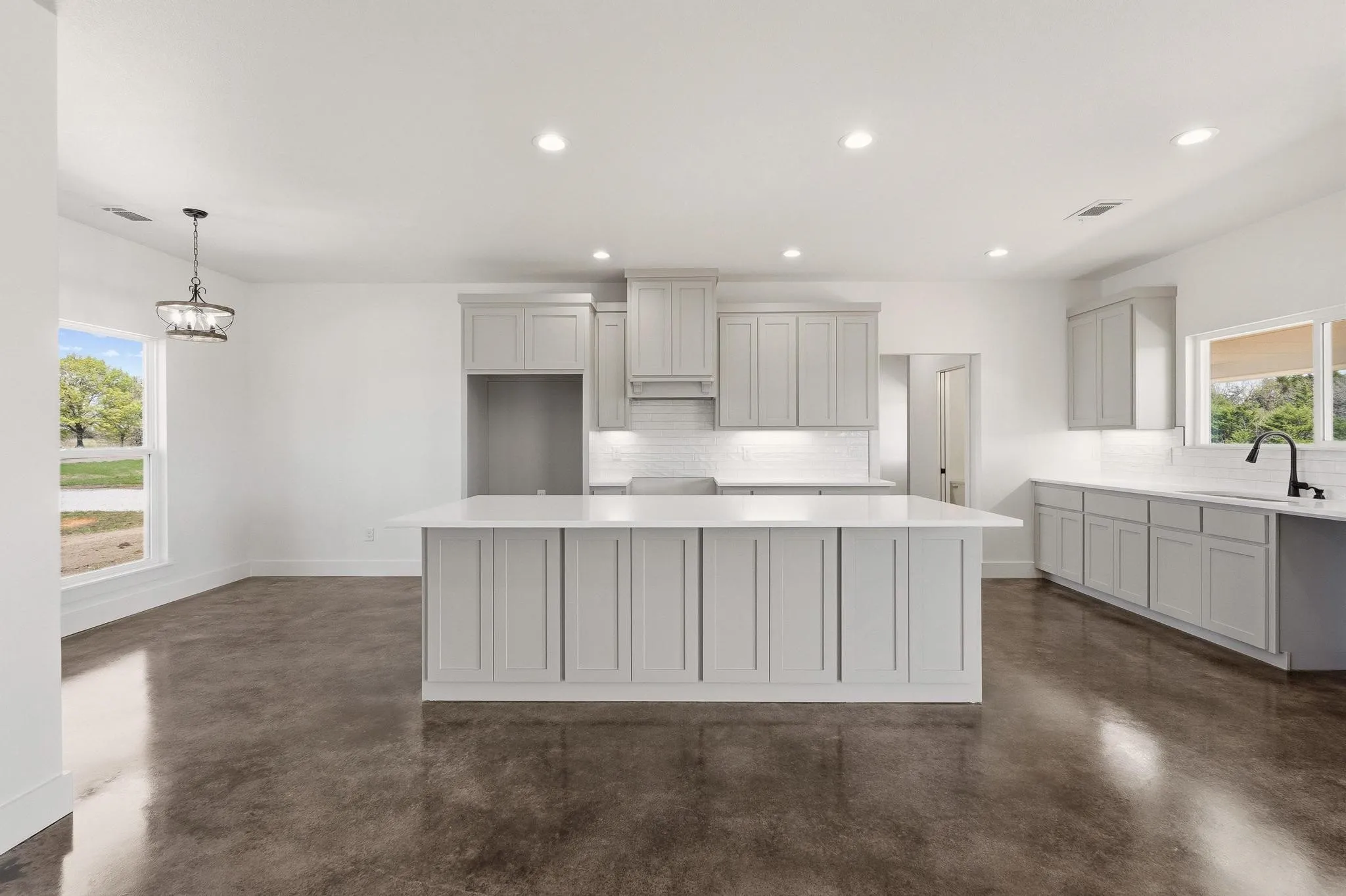 The kitchen features a center island with a white countertop, light gray cabinetry, and a white subway tile backsplash