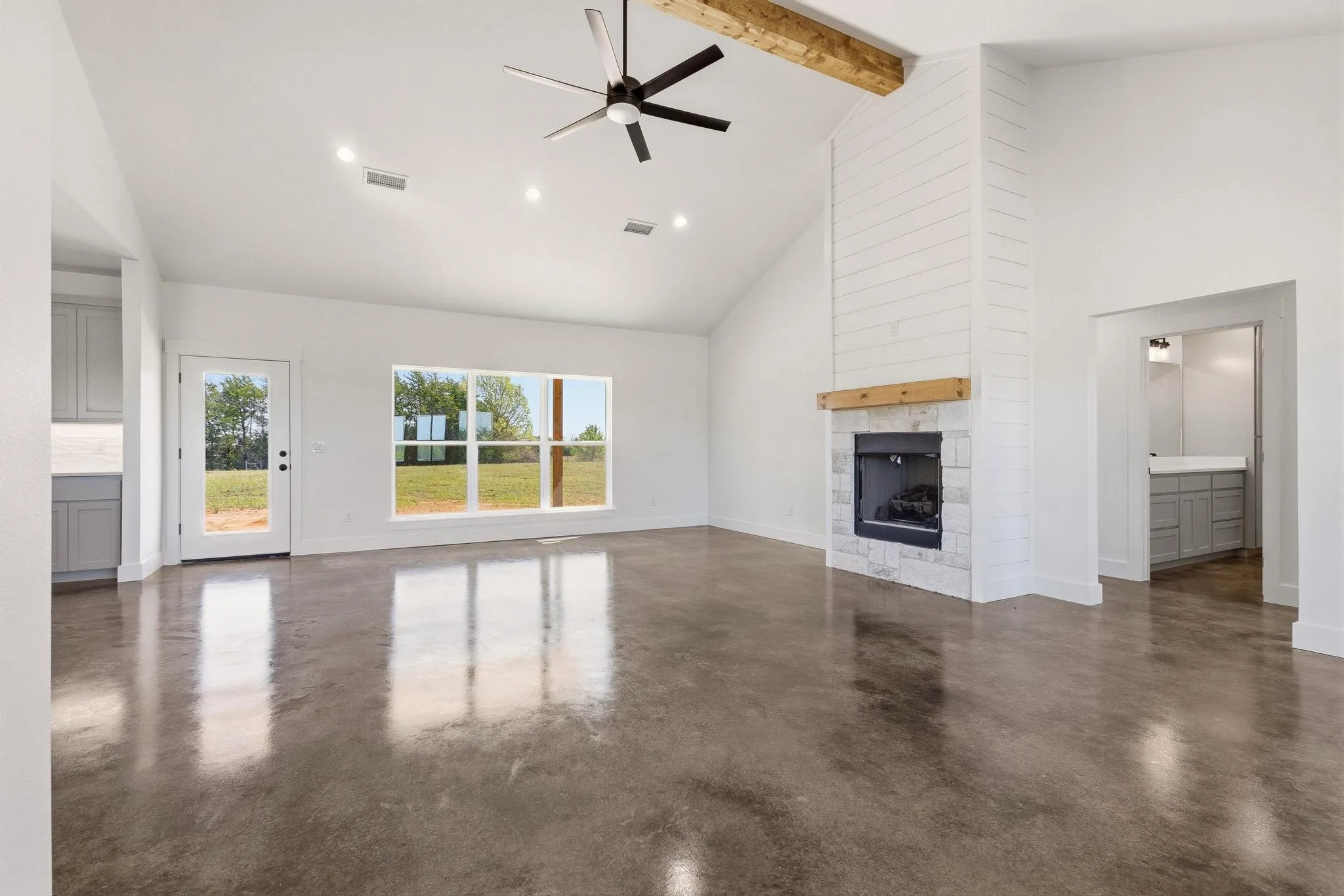 Spacious living area featuring polished concrete floors, a vaulted ceiling with a ceiling fan, and recessed lighting