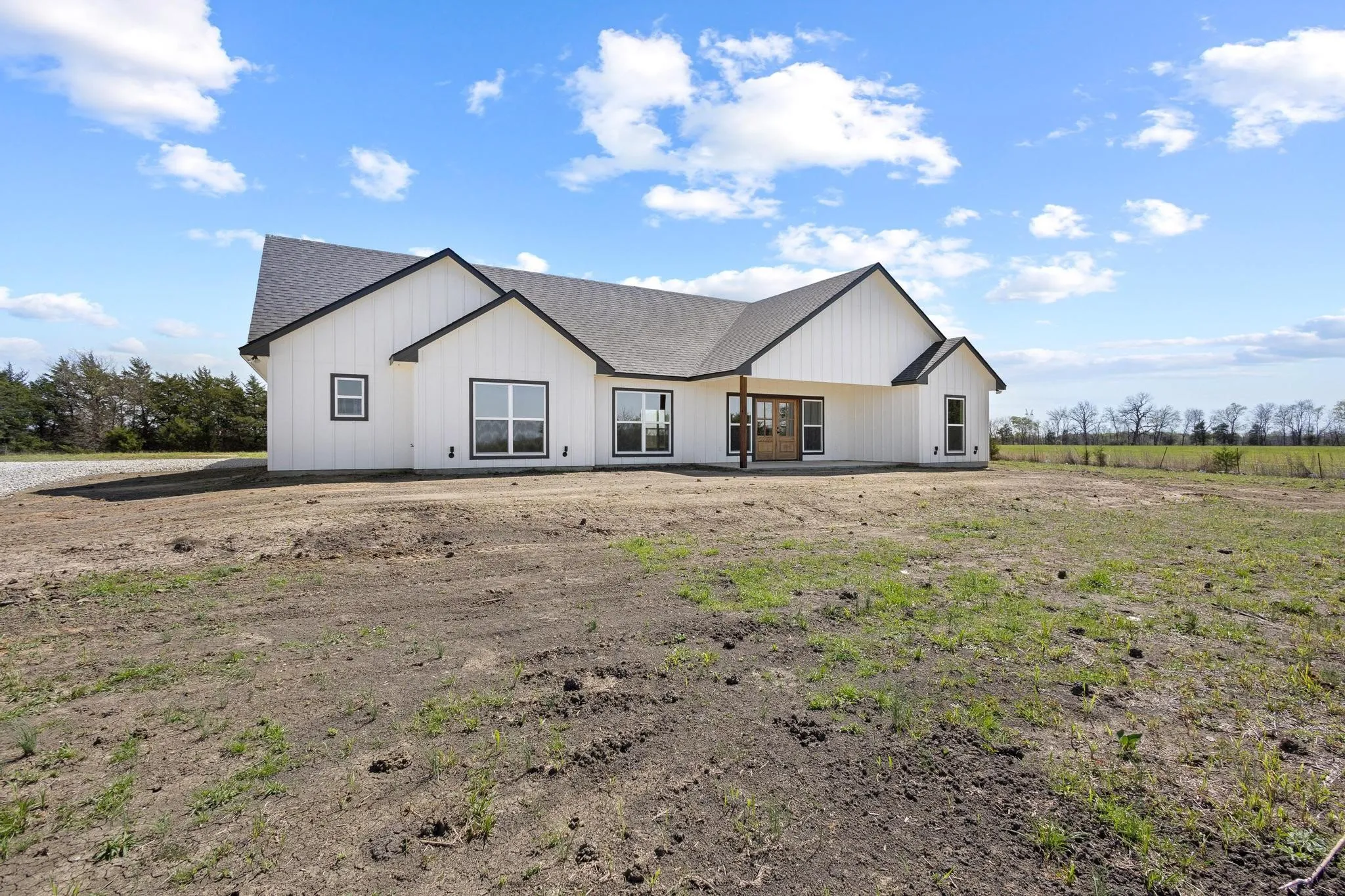 The property features a white exterior with black trim, a dark gray roof, and prominent windows providing ample natural light