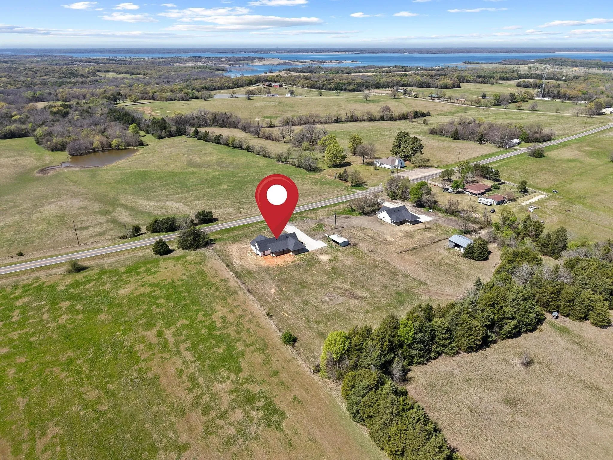 Aerial view of the property, located in a rural setting with expansive green fields and distant water views