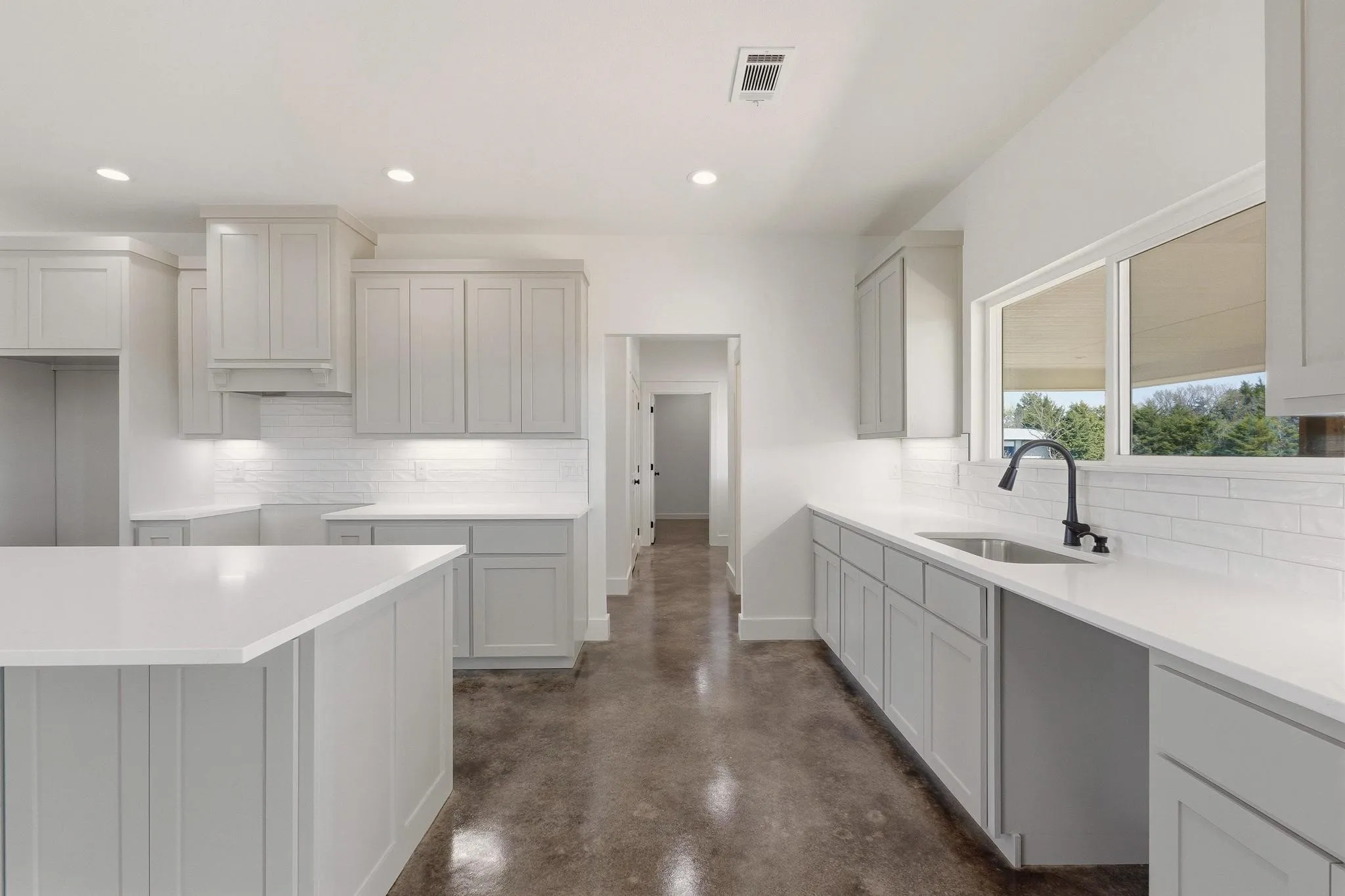 The kitchen features an island, white countertops, gray cabinetry, and a white subway tile backsplash