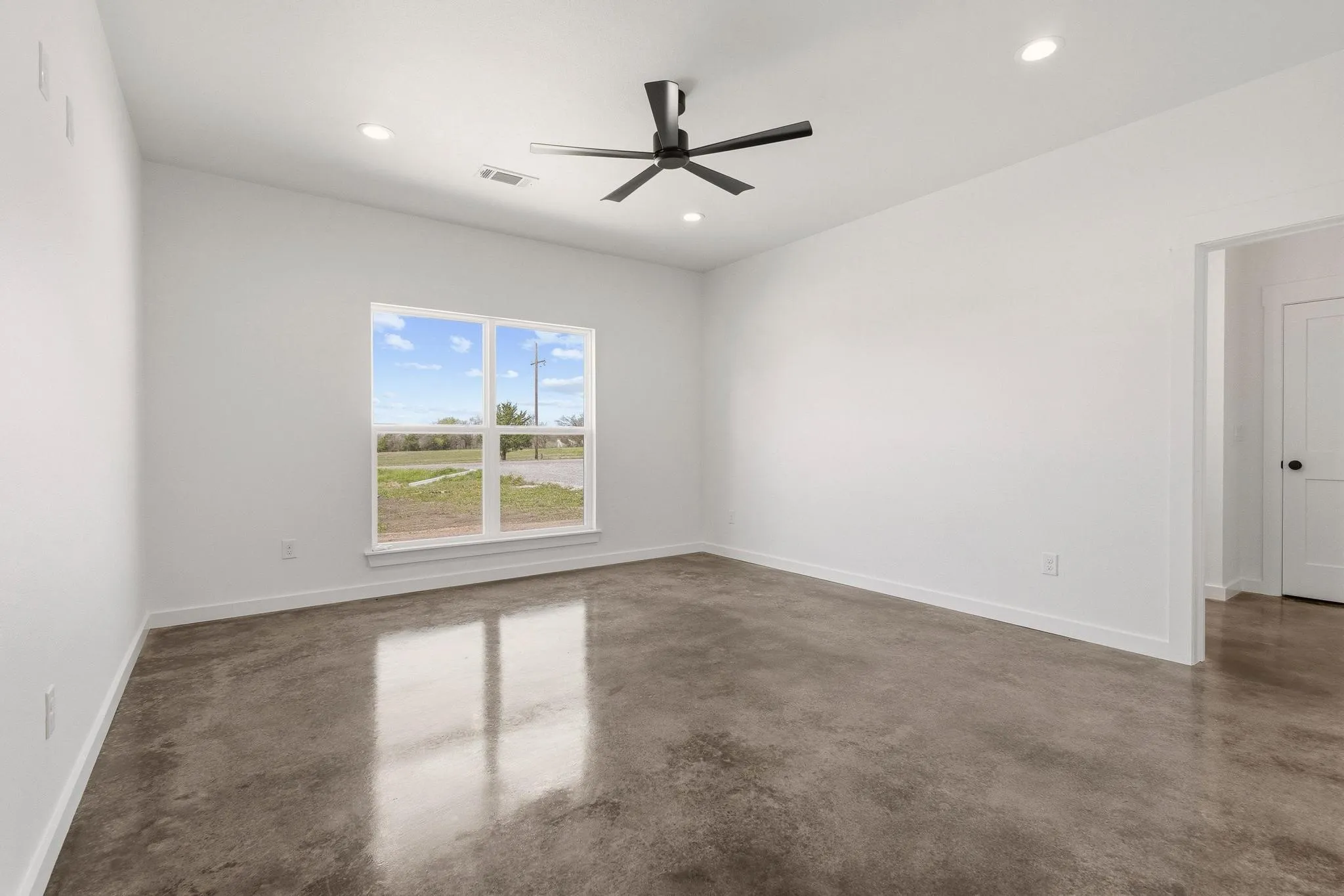 This room features polished concrete floors, a modern ceiling fan, and recessed lighting