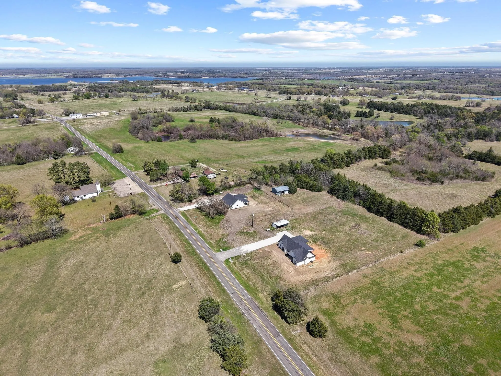 This property features a single-story home with a dark roof, situated on a large lot with extensive green spaces