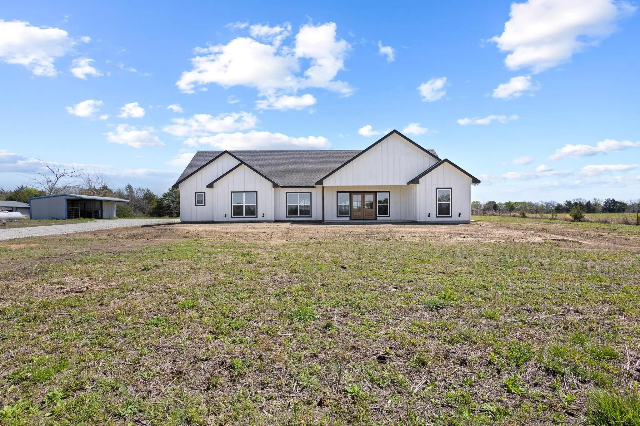 This property features a modern farmhouse-style exterior with white vertical siding, black-trimmed windows, and a dark shingled roof