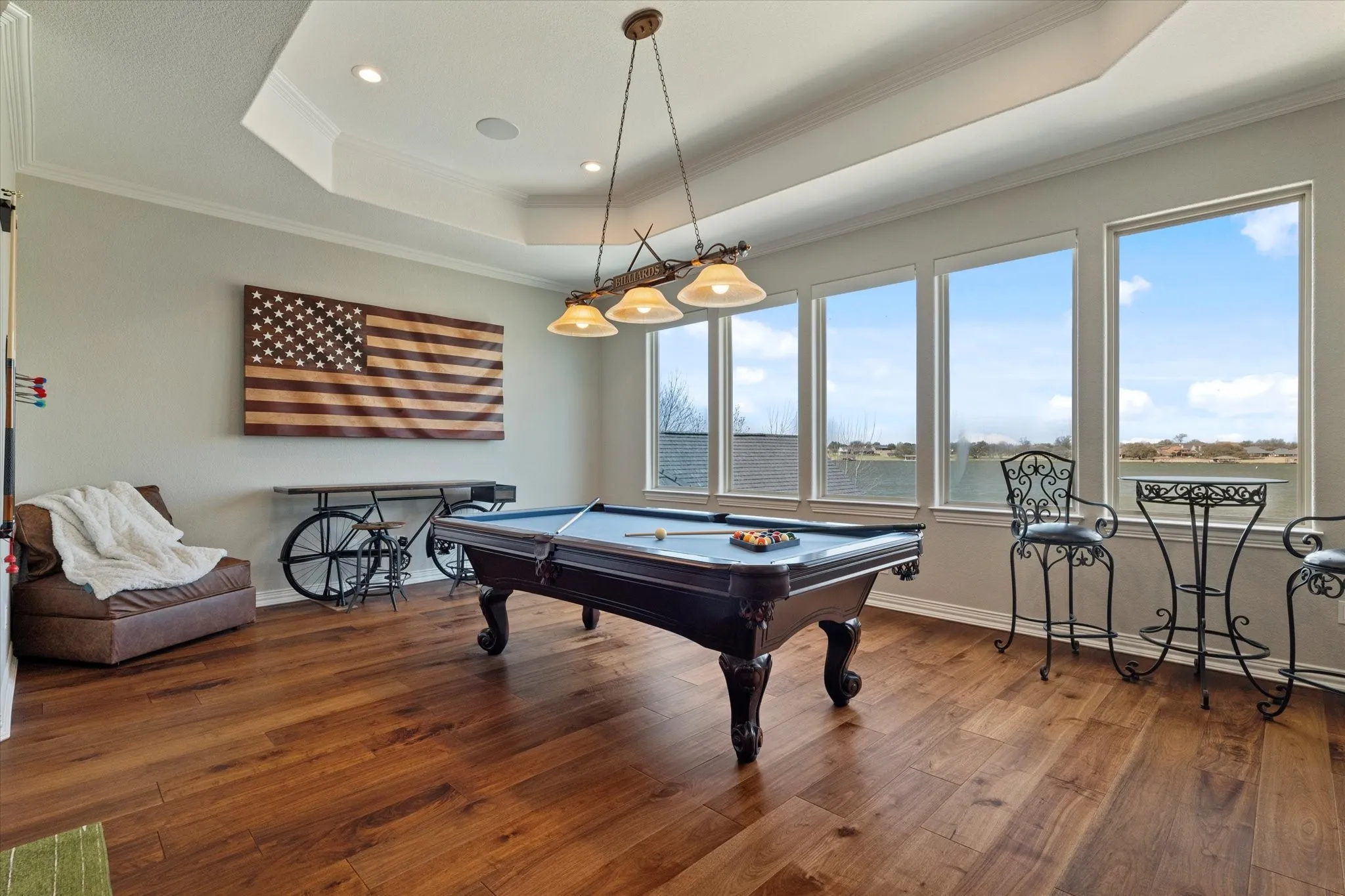 This versatile room features hardwood floors, a tray ceiling with recessed lighting, and a chandelier