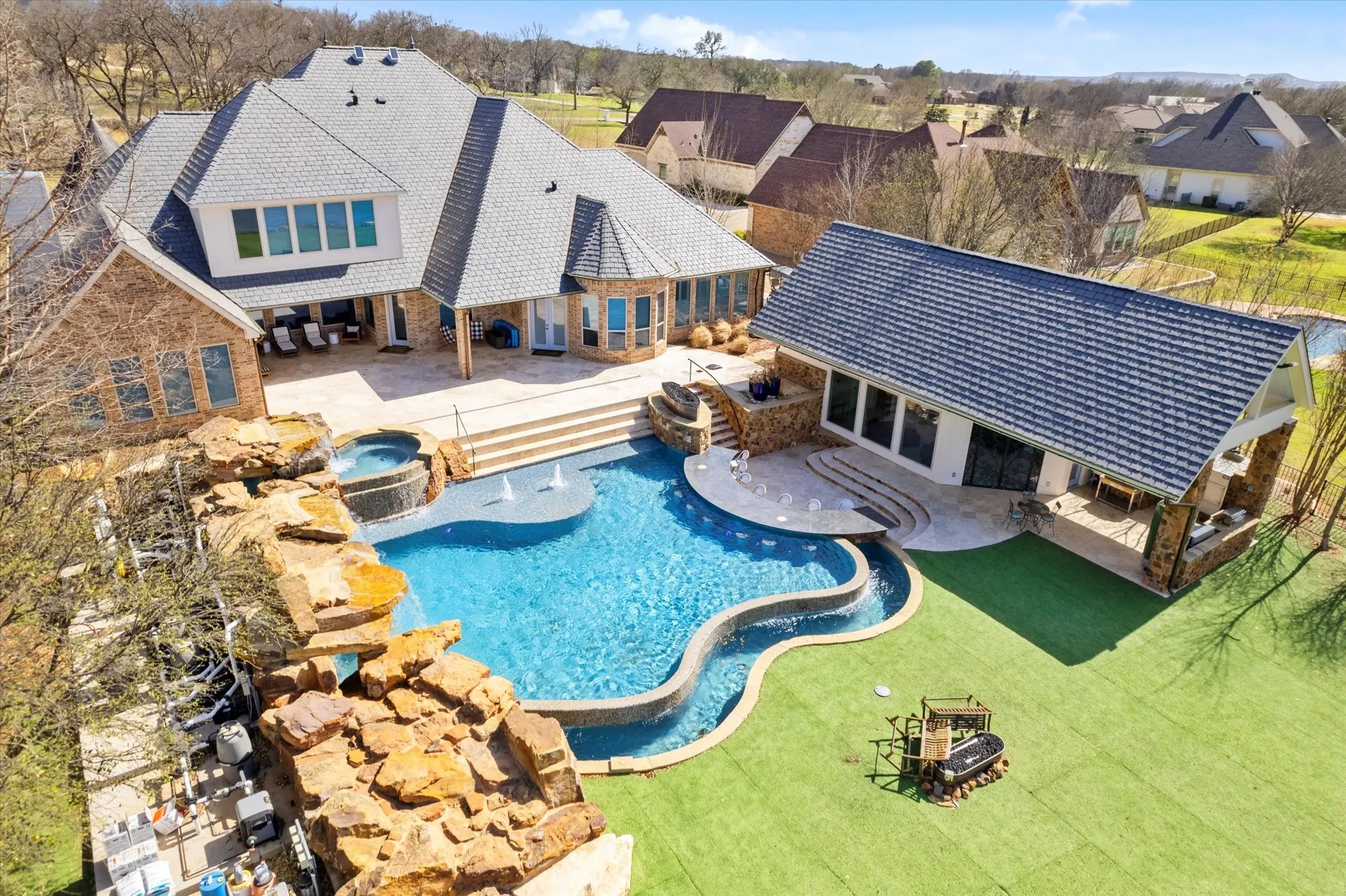 The property features an extensive backyard with a custom-shaped pool, an integrated spa, and a rock waterfall