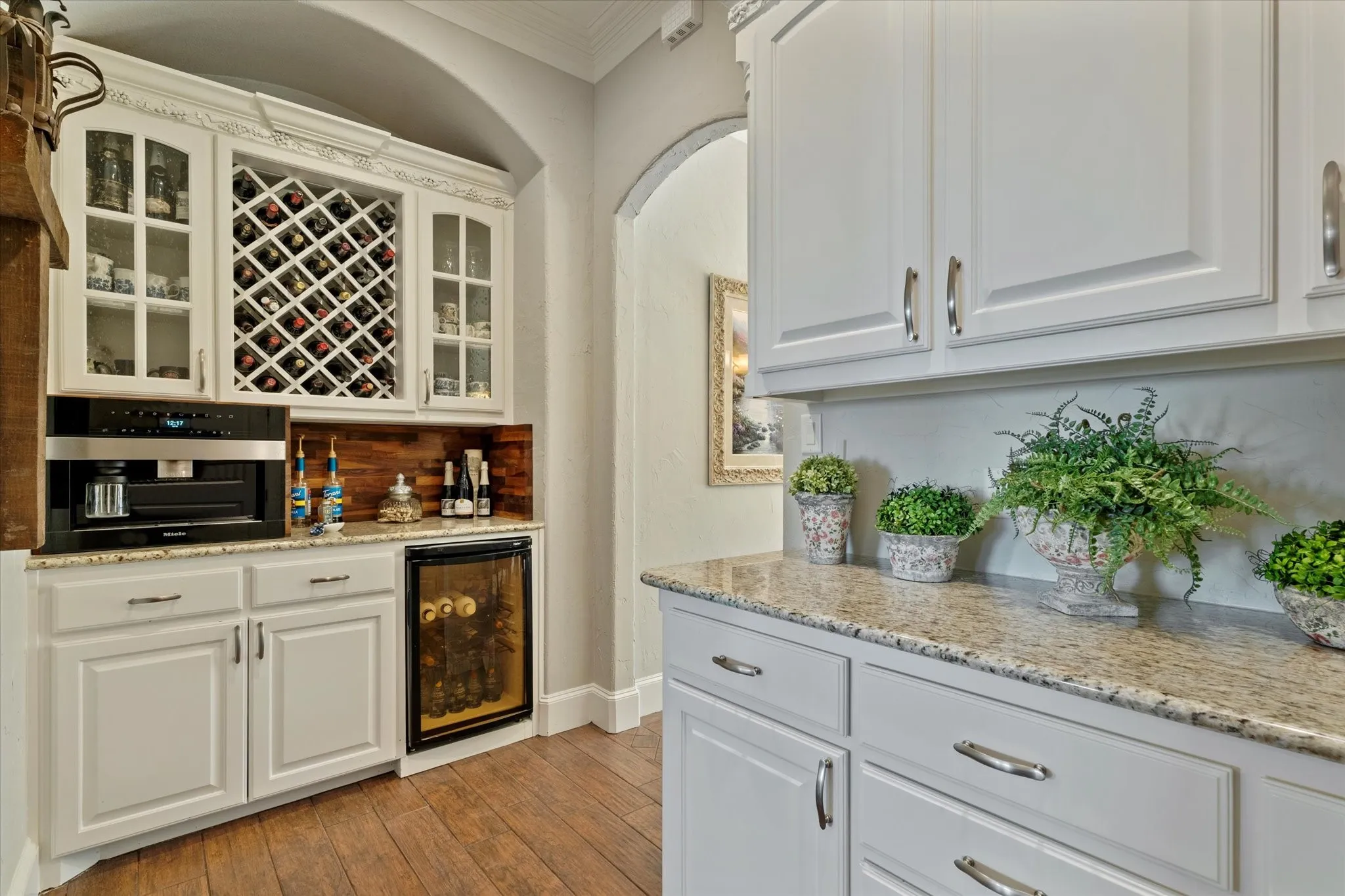 This space features extensive white cabinetry, a built-in wine rack, and a beverage cooler