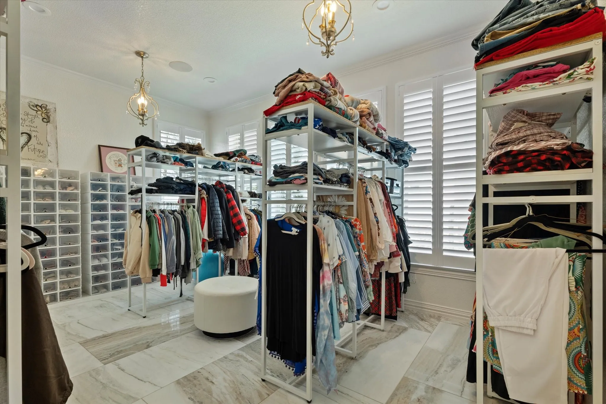 The property includes a spacious room featuring decorative chandeliers, window shutters, and a light-toned tile floor