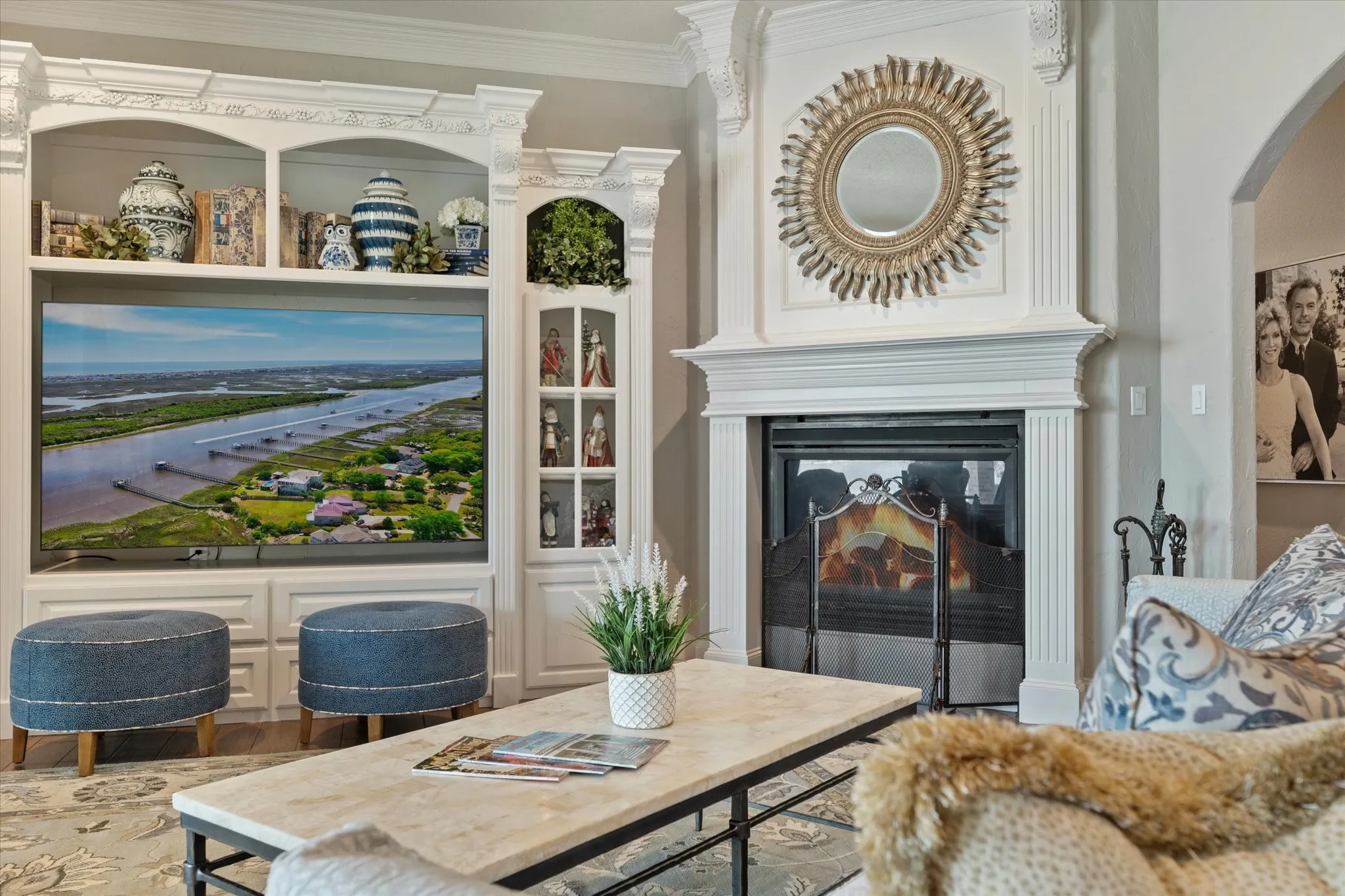 The living area features a built-in media center with decorative shelving, a fireplace with a detailed mantel, and an arched doorway