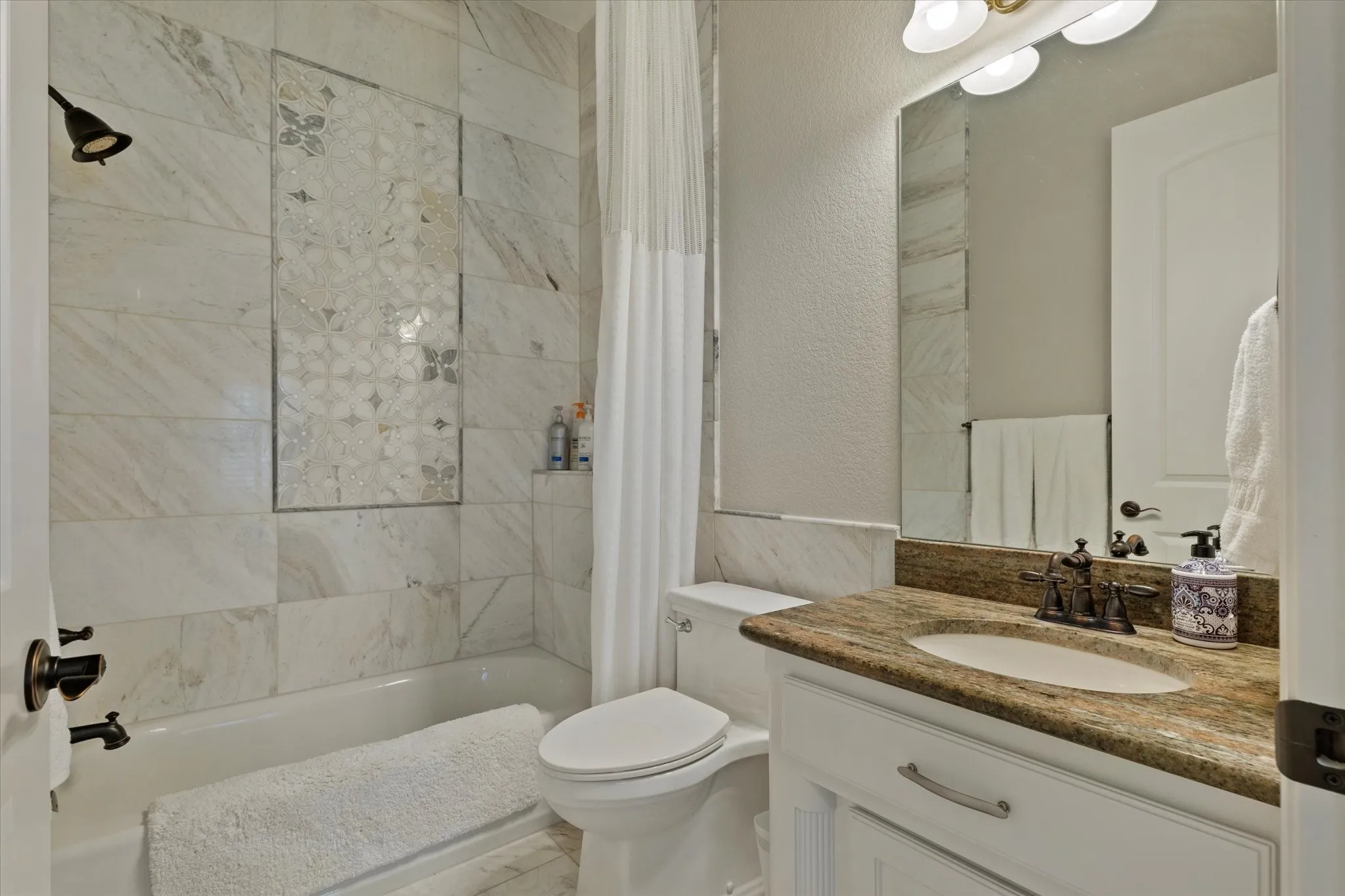 The bathroom features a bathtub and shower combination with tile surround, a vanity with a granite countertop, and a single sink