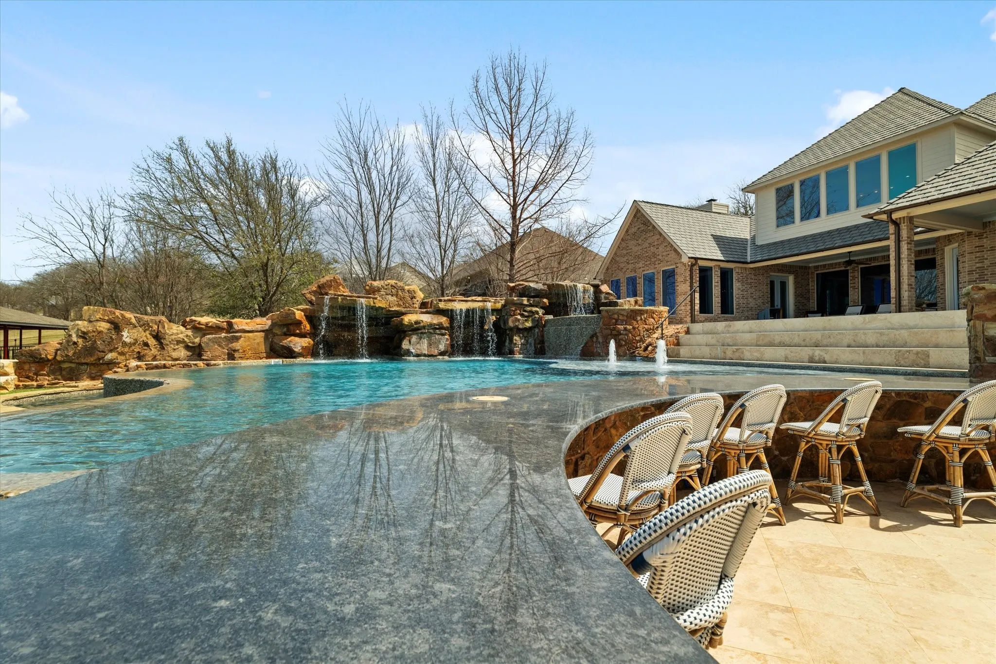 The property features an expansive outdoor pool with rock waterfalls and a built-in bar area with seating