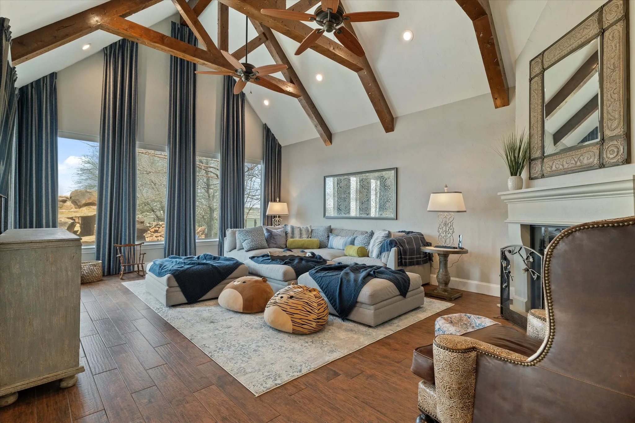 The living area features vaulted ceilings with exposed wood beams, hardwood flooring, and a fireplace with a decorative mantel and mirror