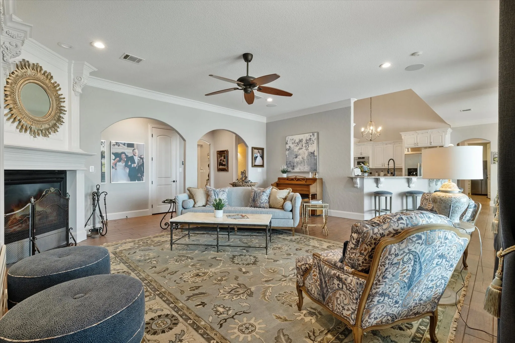Spacious living area featuring a fireplace with decorative molding, arched doorways, and a ceiling fan