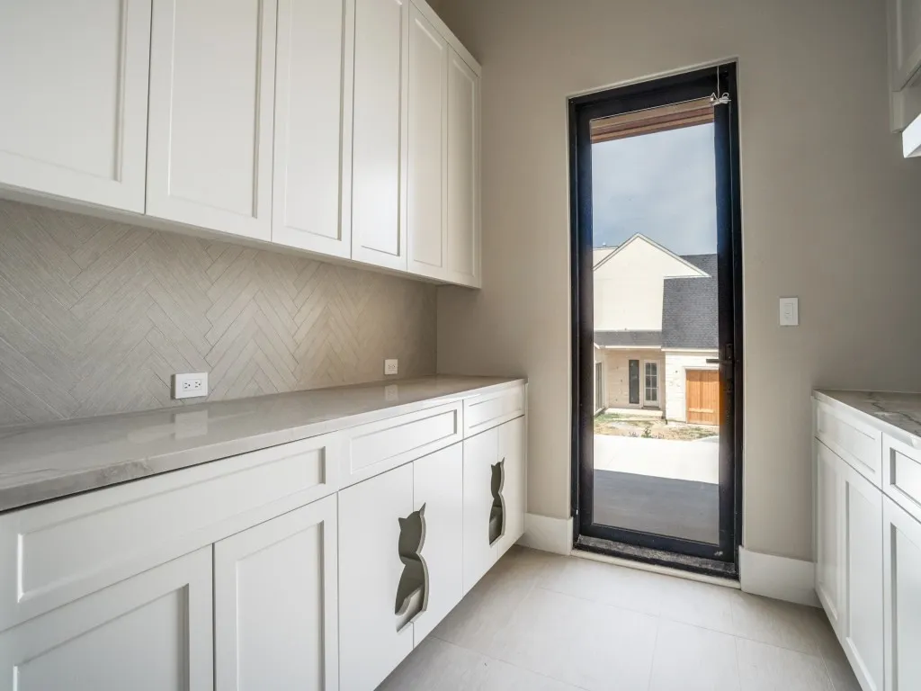 Custom cabinetry in the laundry room is perfect for pet lovers. There is also a laundry sink, clothes steamer, utility closet, and ample cabinet space.