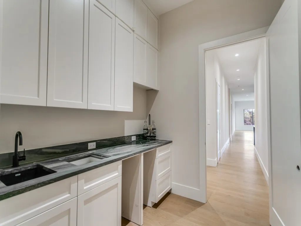 Near the media room, this wet bar features a beverage center, ample storage, and a candy drawer.