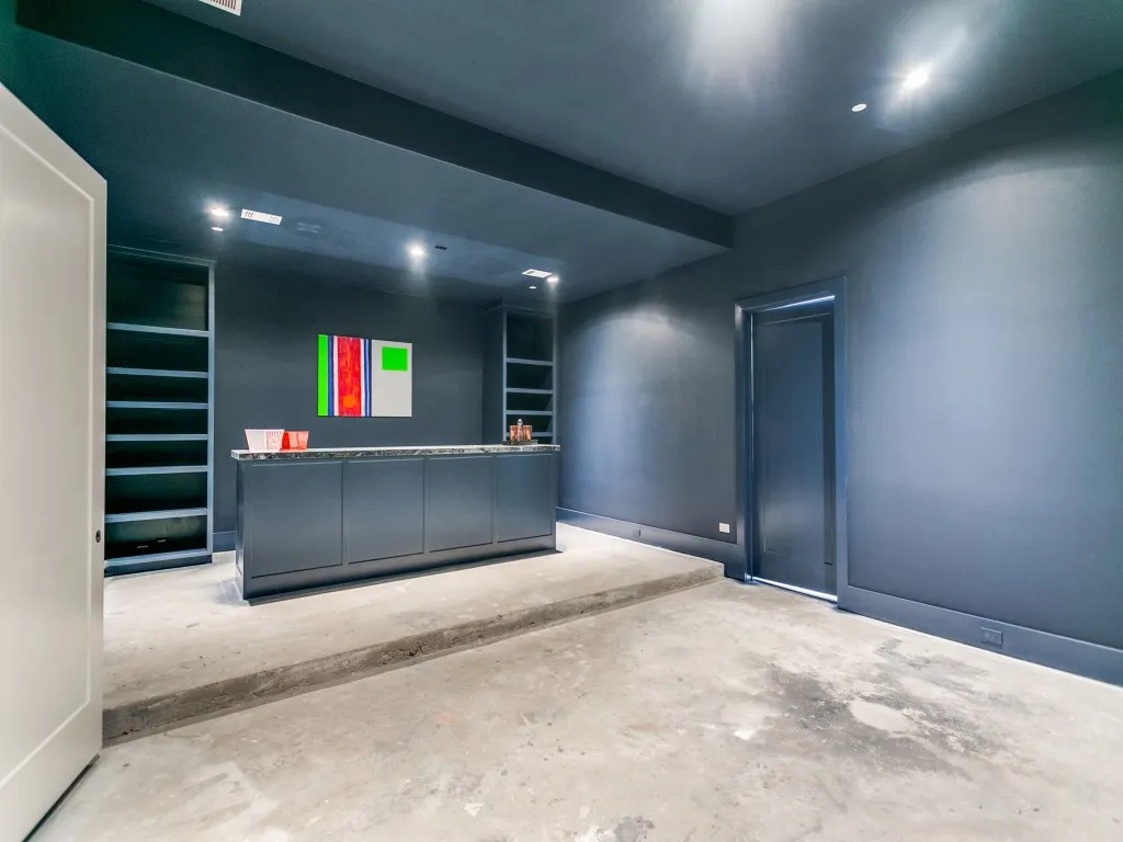 Media room features a substantial bar flanked by custom built in shelving.