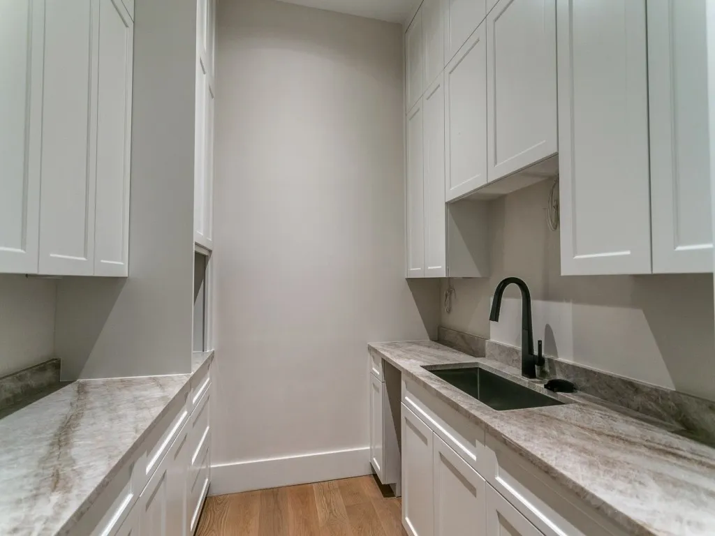 The prep-kitchen located just off the main kitchen features a sink, custom cabinetry, and space for a built in coffee maker, full size wine fridge, and small appliances.