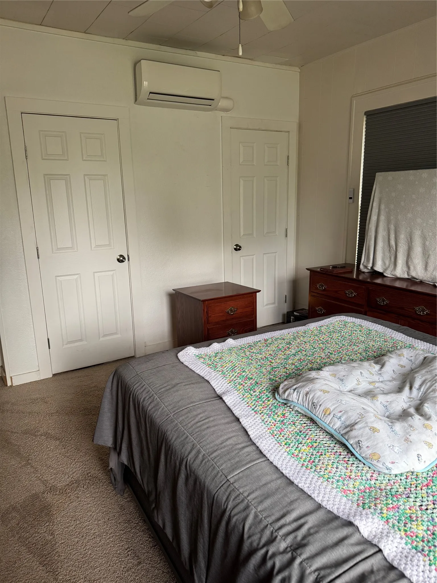 Bedroom featuring dark carpet, a wall mounted mini split, and a ceiling fan