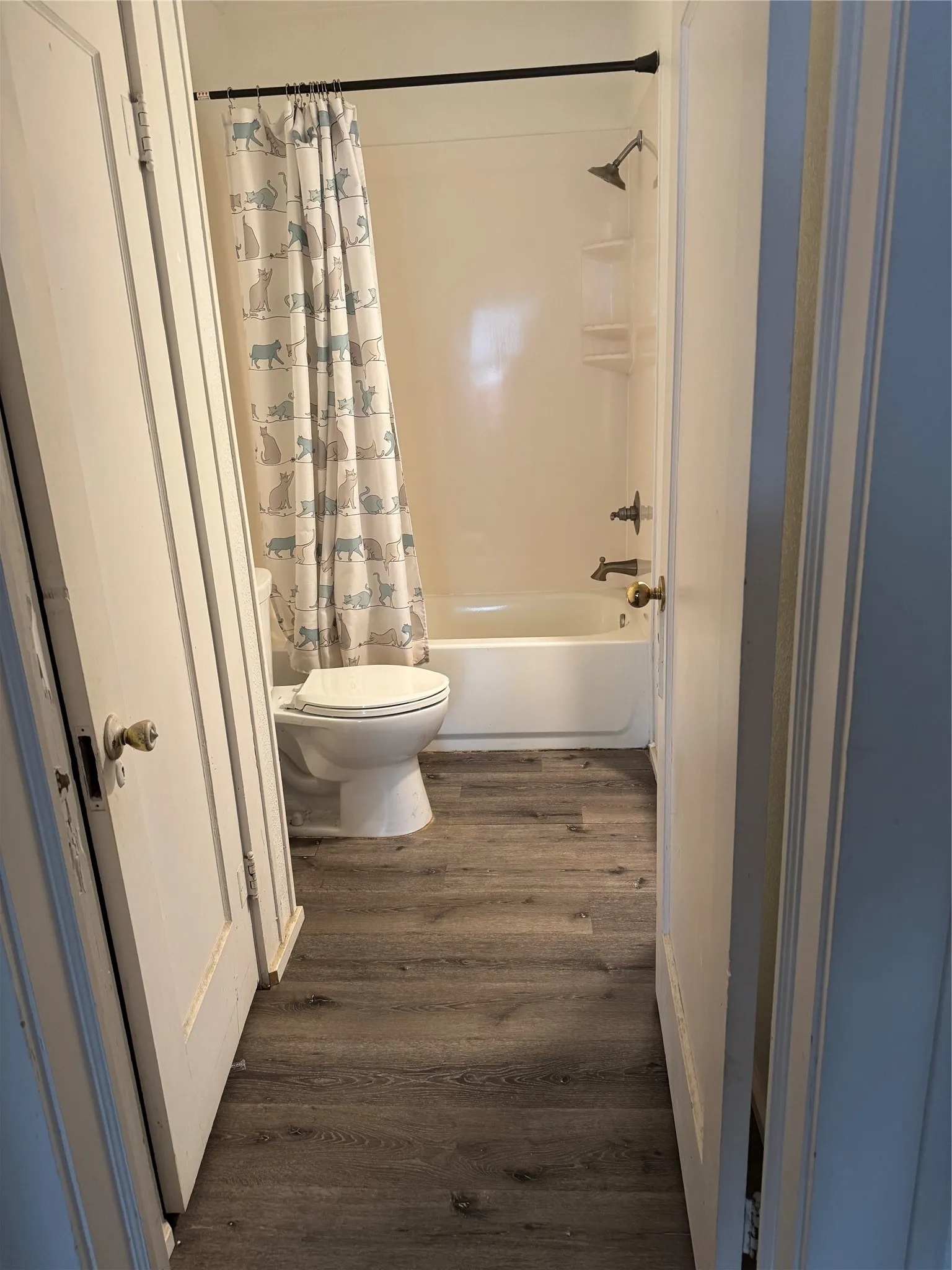 Full bathroom featuring dark wood-type flooring and shower / bath combination with curtain
