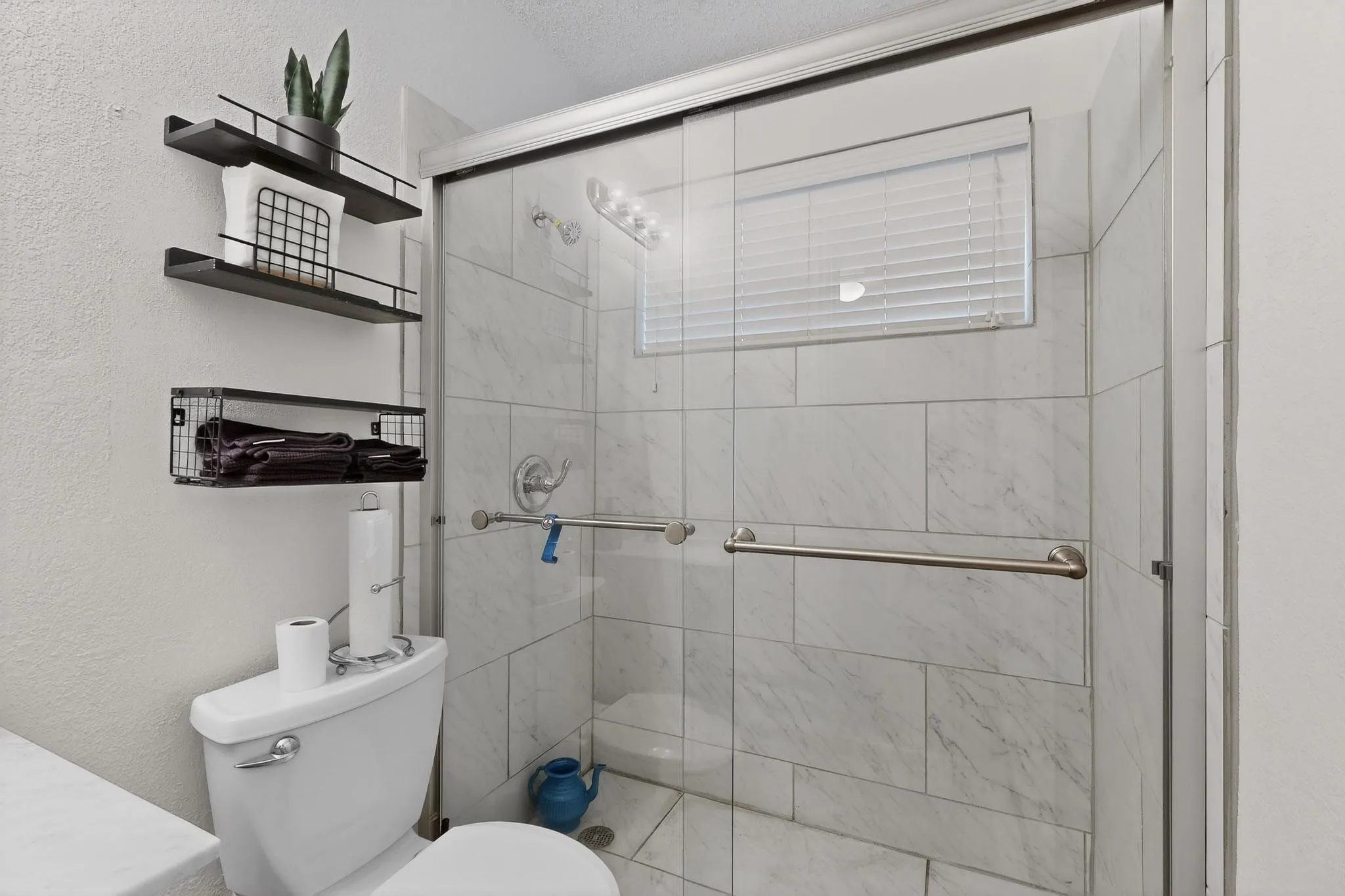 Bathroom with a shower stall, a textured wall, and vanity