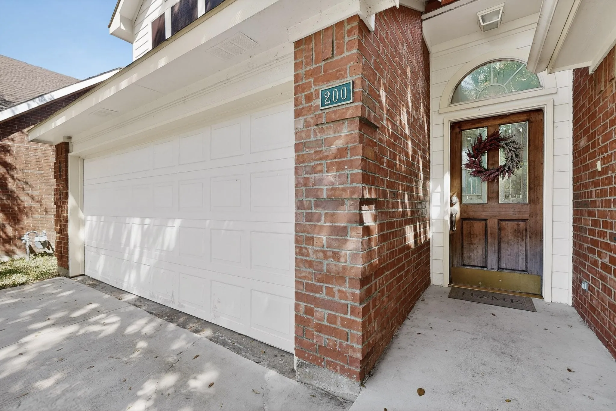 View of exterior entry featuring brick siding, driveway, and a garage