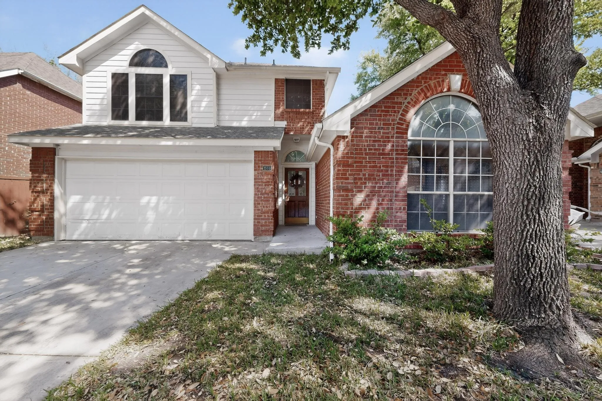 Traditional-style house with an attached garage, brick siding, and driveway