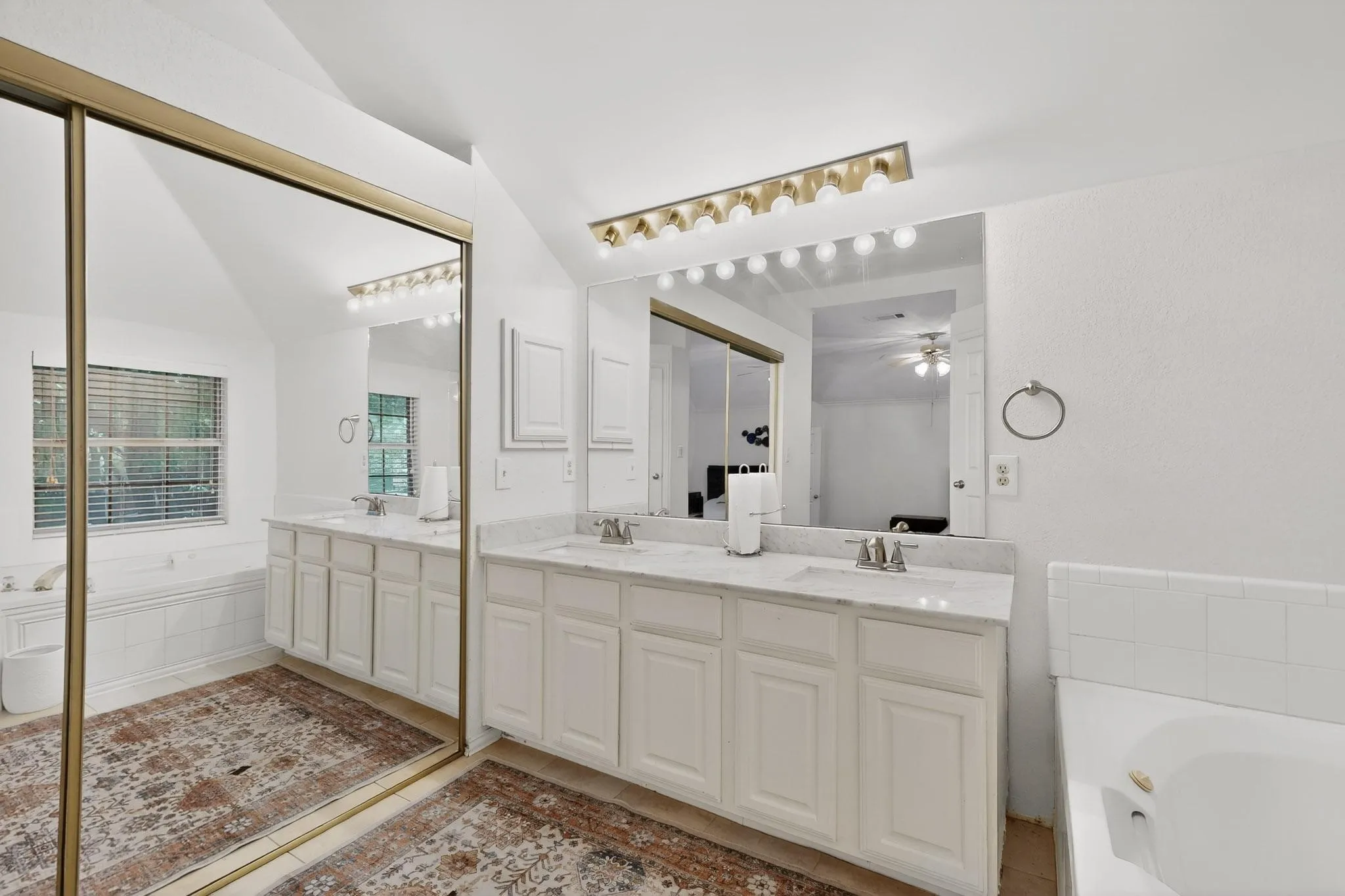 Bathroom featuring a garden tub, double vanity, light tile patterned floors, and ceiling fan