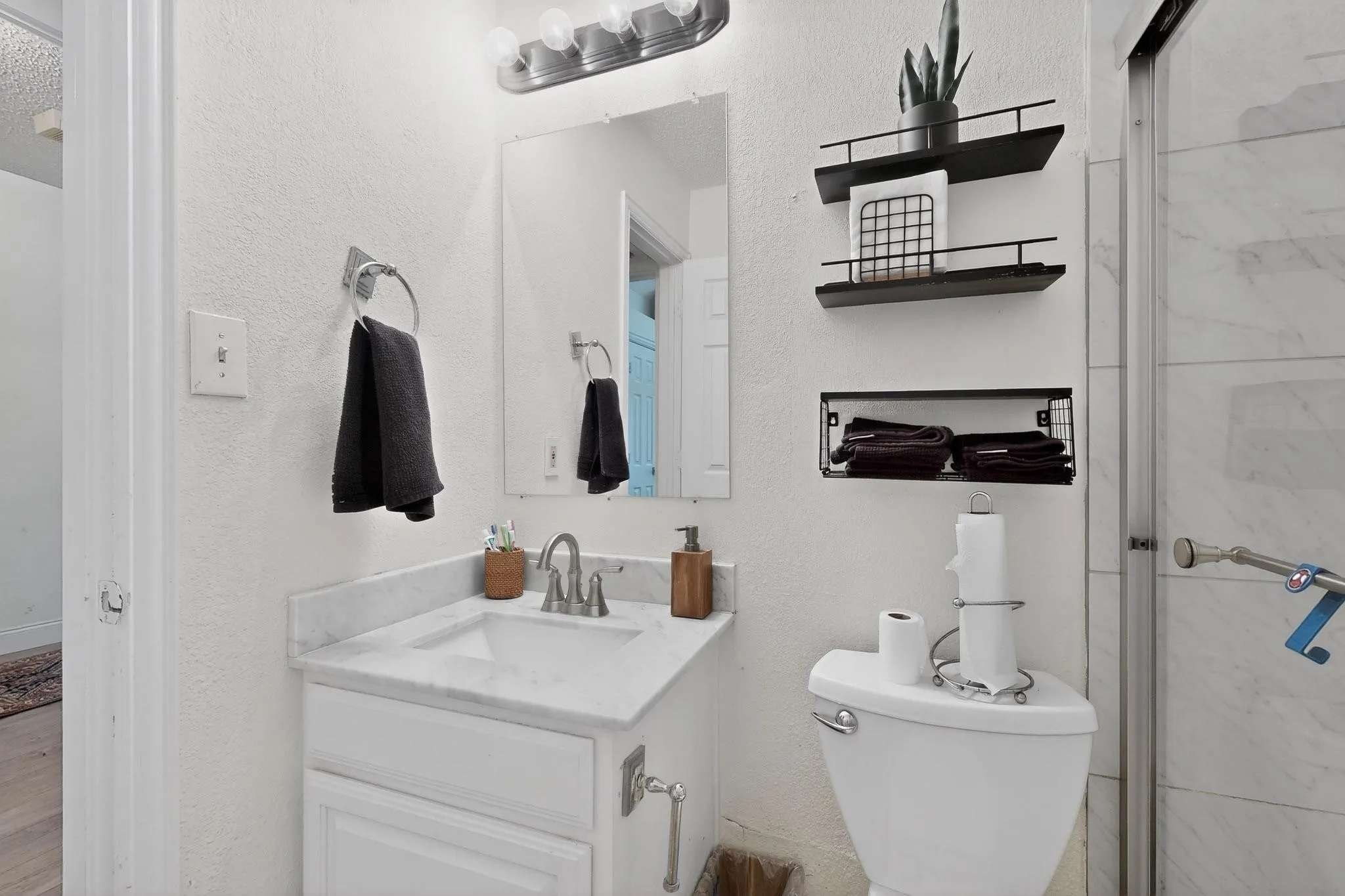 Full bath with vanity, a textured wall, and a stall shower