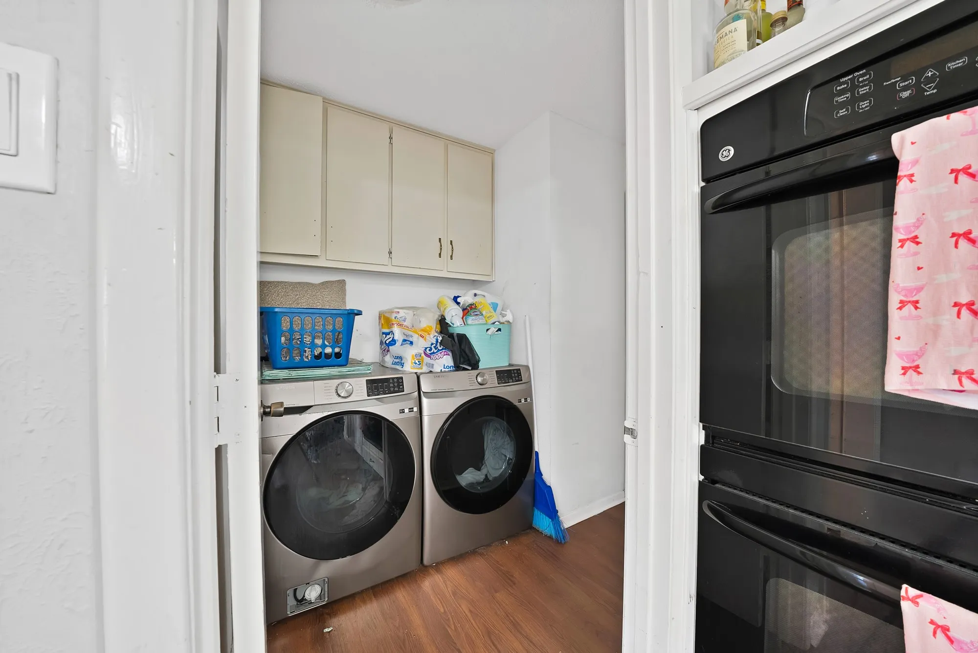 Laundry room featuring dark wood-style floors, washing machine and dryer, and cabinet space