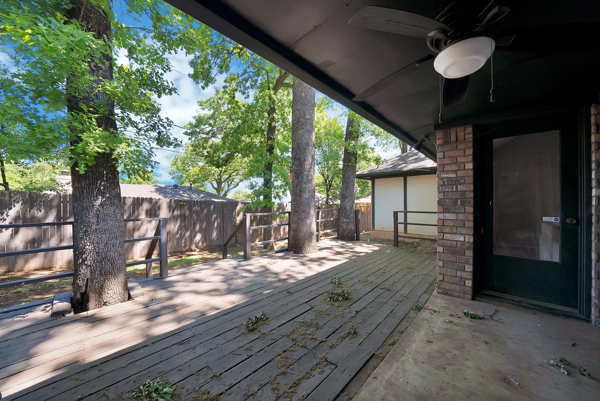 Wooden deck with a ceiling fan and a fenced backyard