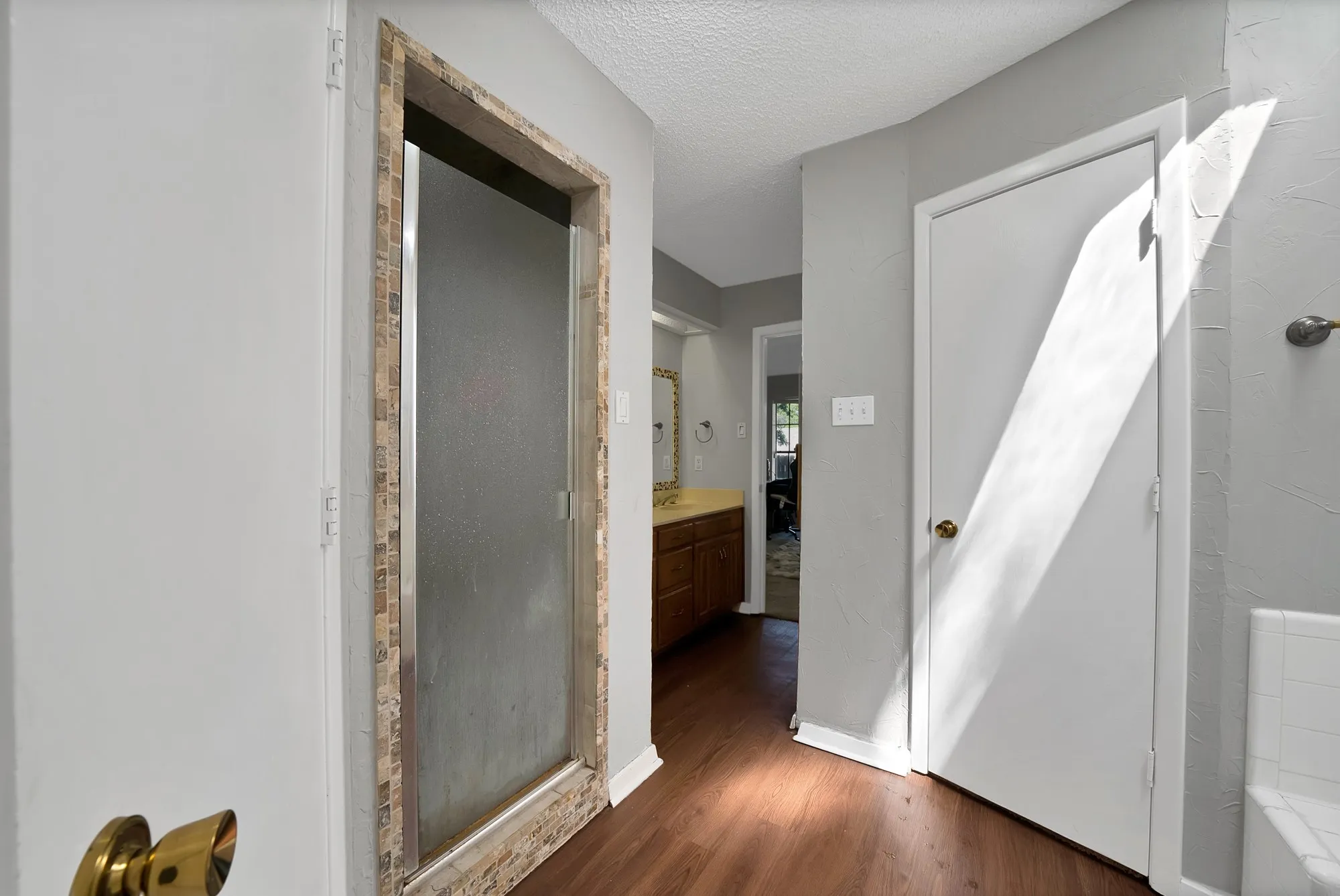 Full bathroom featuring a shower stall, a textured ceiling, dark wood-style floors, and vanity