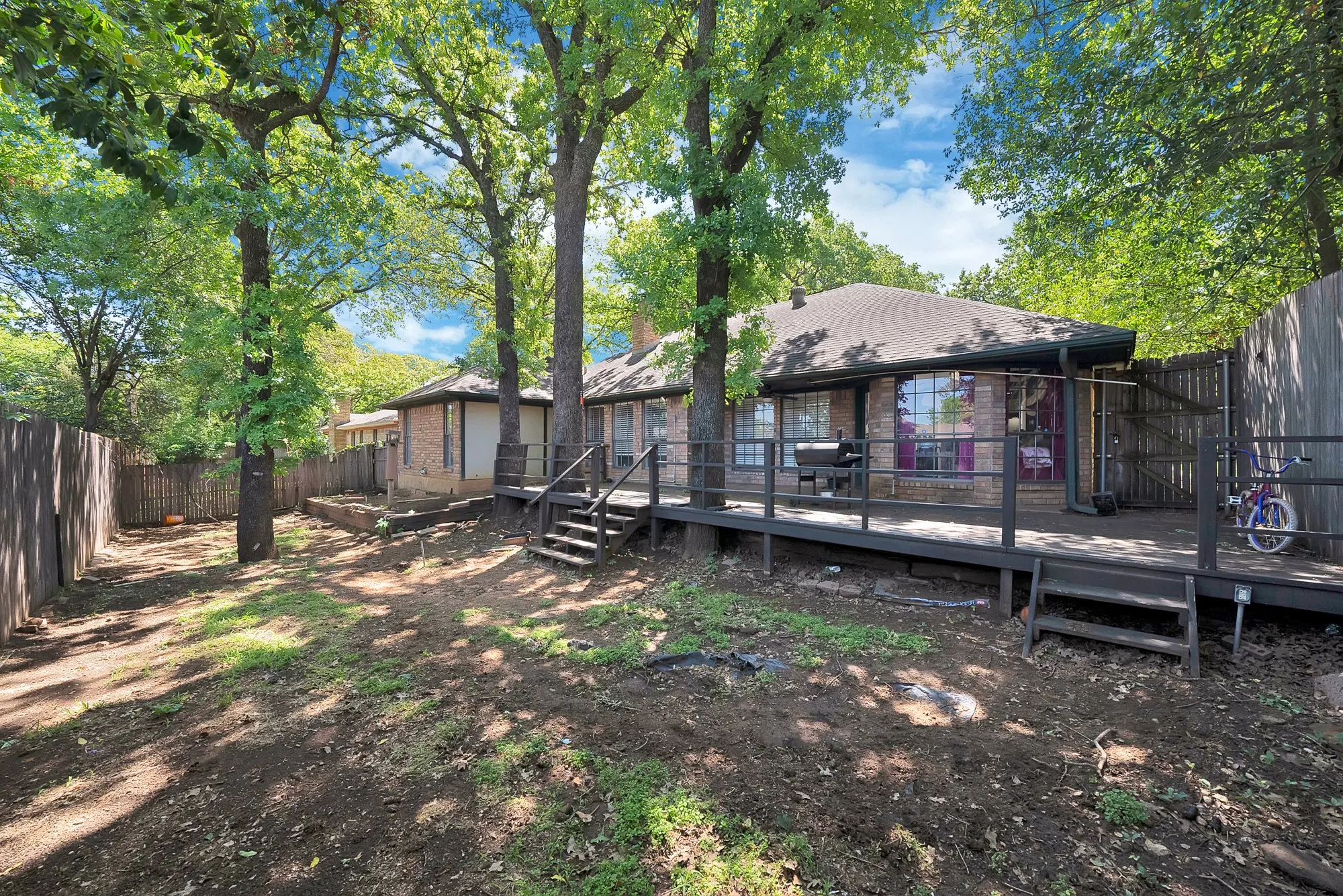 Rear view of house featuring a deck, a fenced backyard, and brick siding