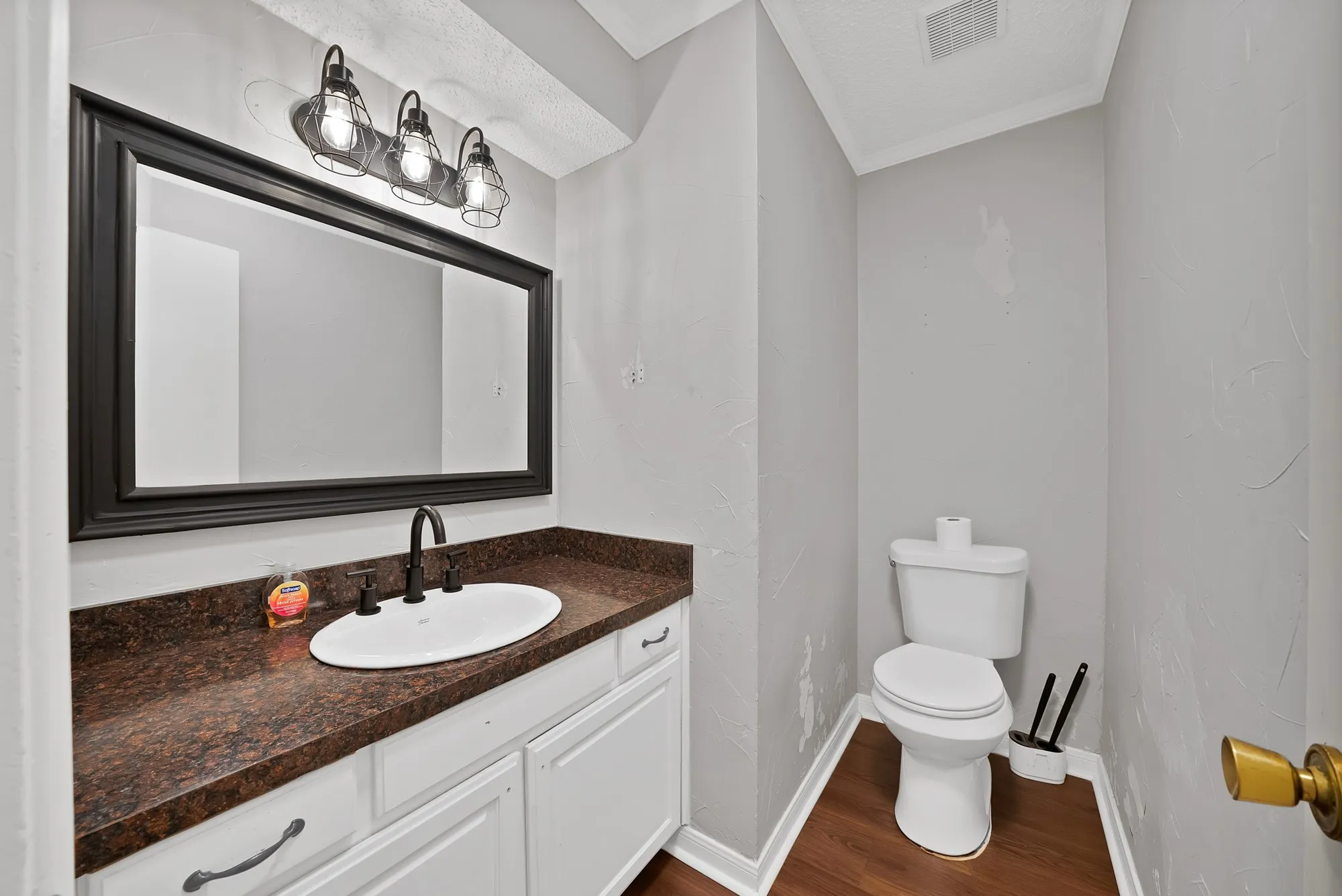 Half bath with vanity, ornamental molding, and dark wood finished floors