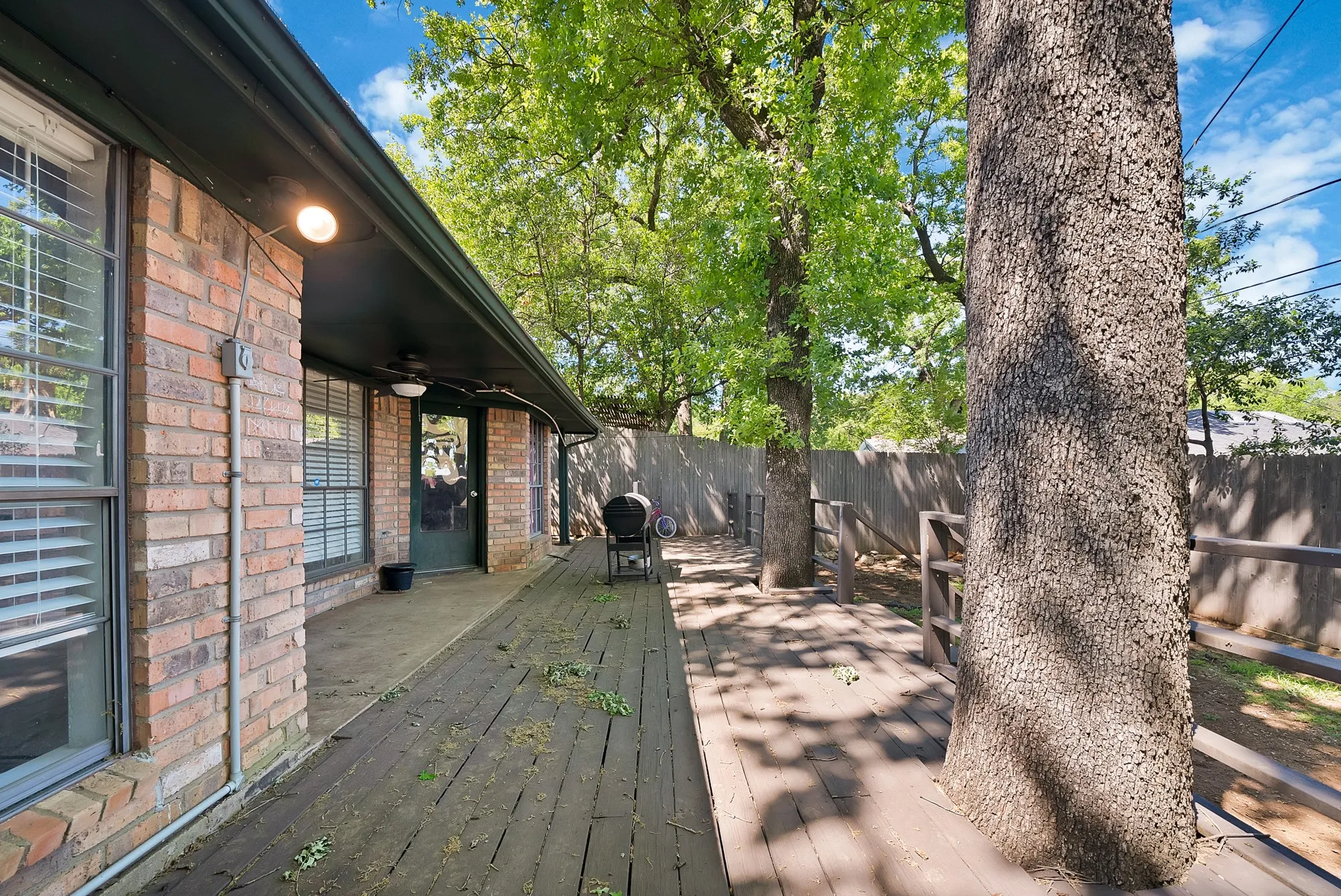 Wooden terrace with a fenced backyard