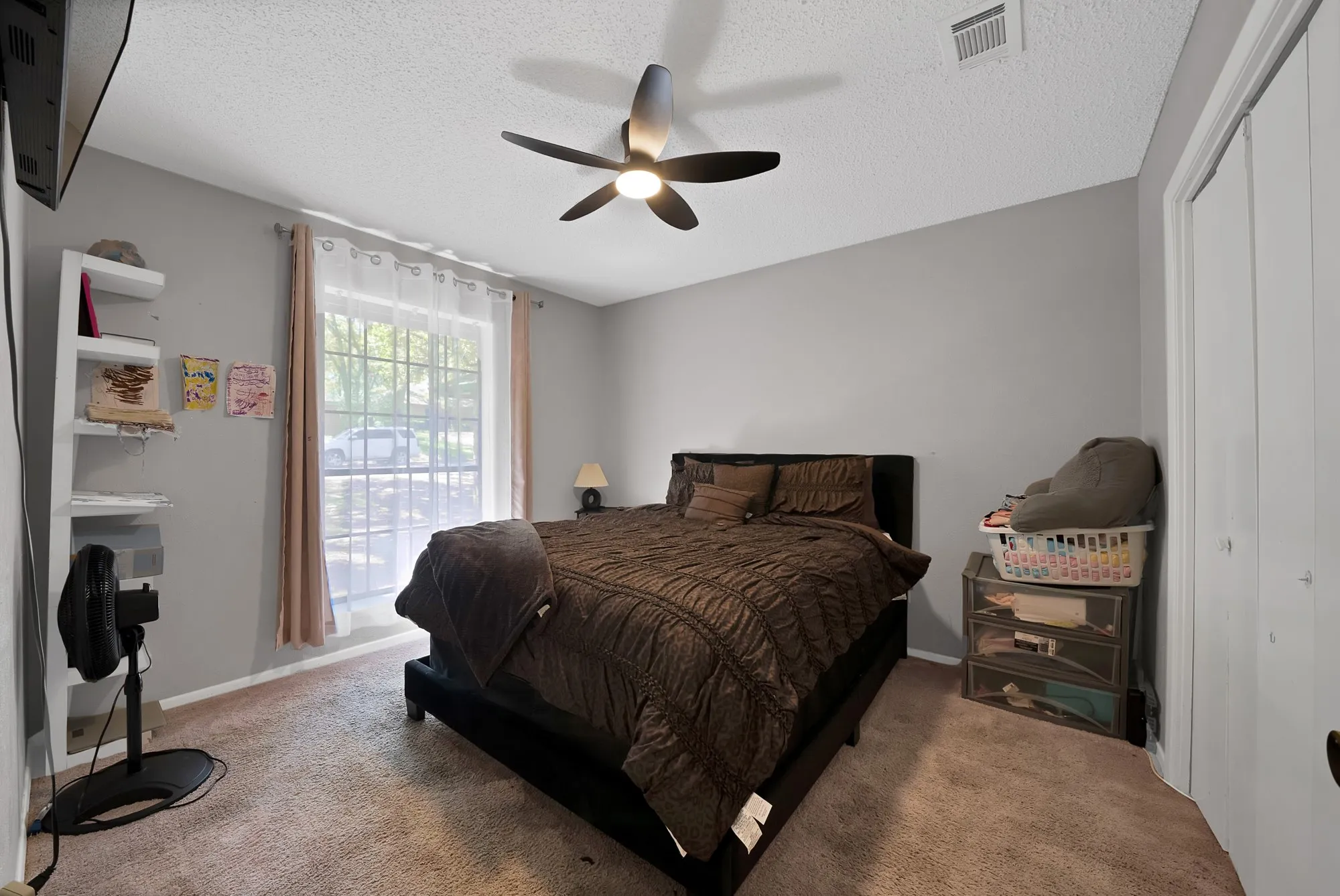 Bedroom with a closet, a textured ceiling, light colored carpet, and ceiling fan