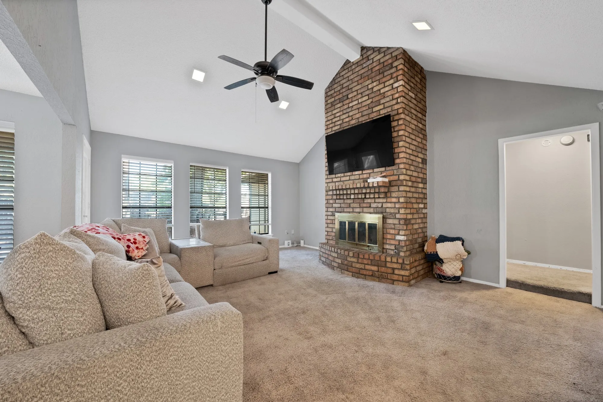 Living area featuring ceiling fan, carpet, and a brick fireplace