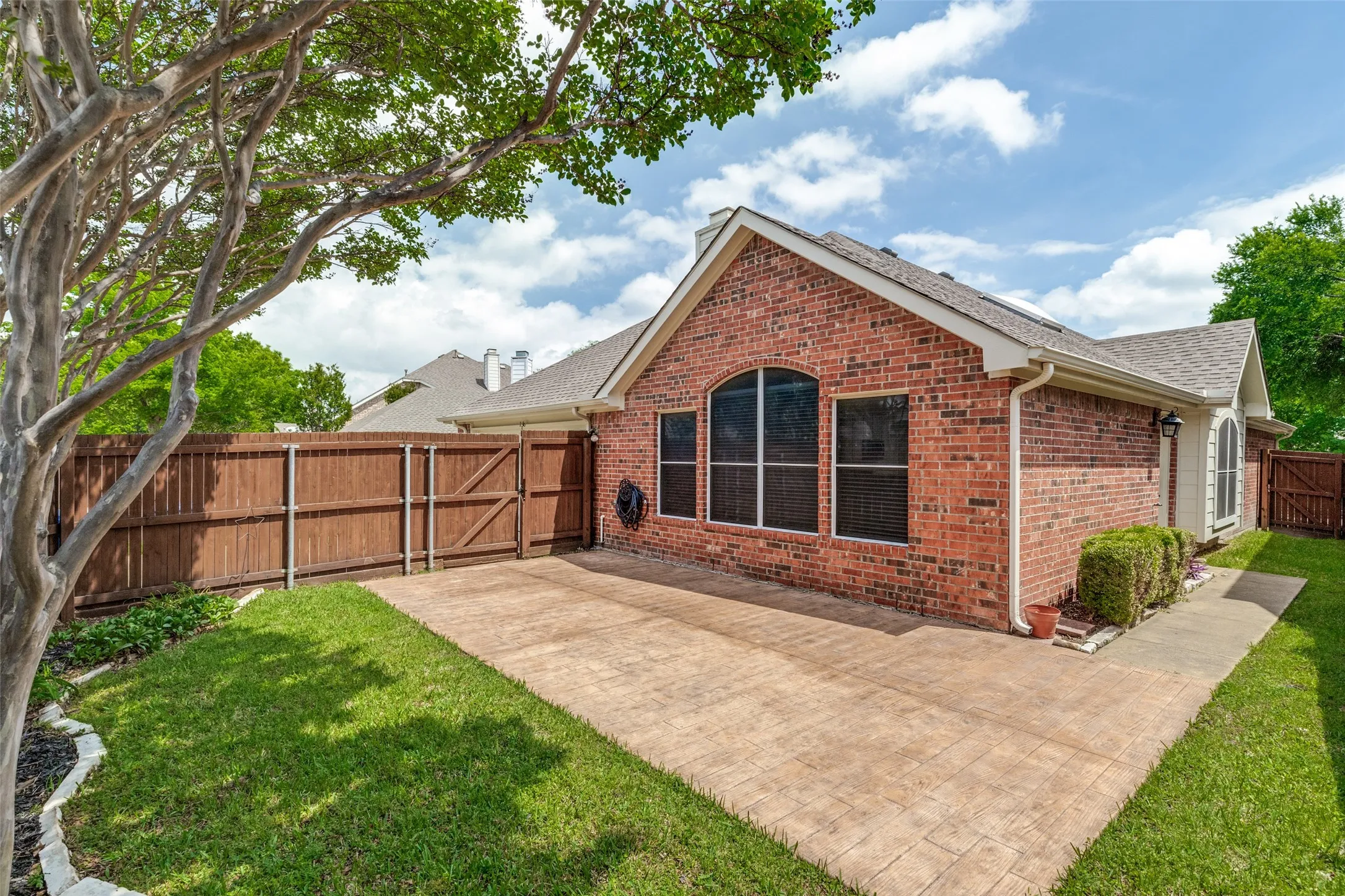 Low-maintainence yard surrounded by nice wood fence with steel posts.