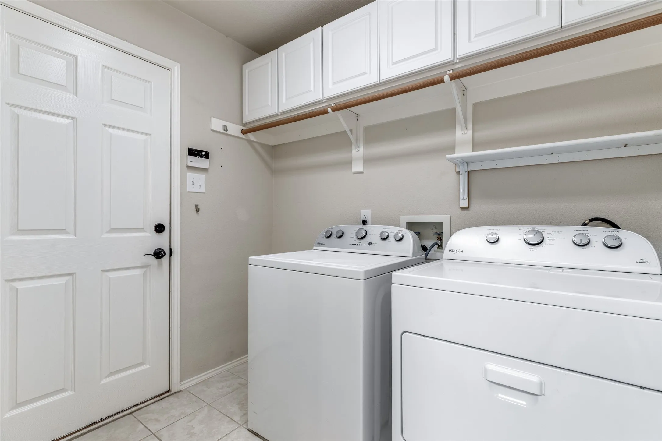 Separate tiled laundry has built-in cabinets and a dry rack.