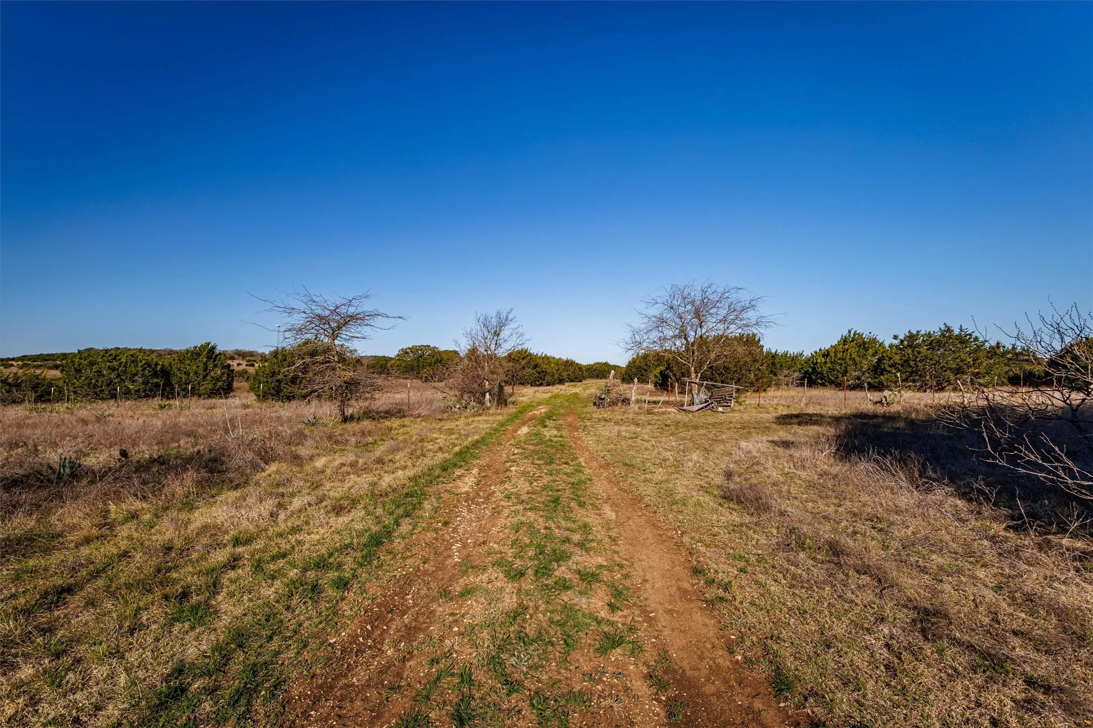 The property features a natural landscape with a clear sky and a visible path, surrounded by trees and vegetation
