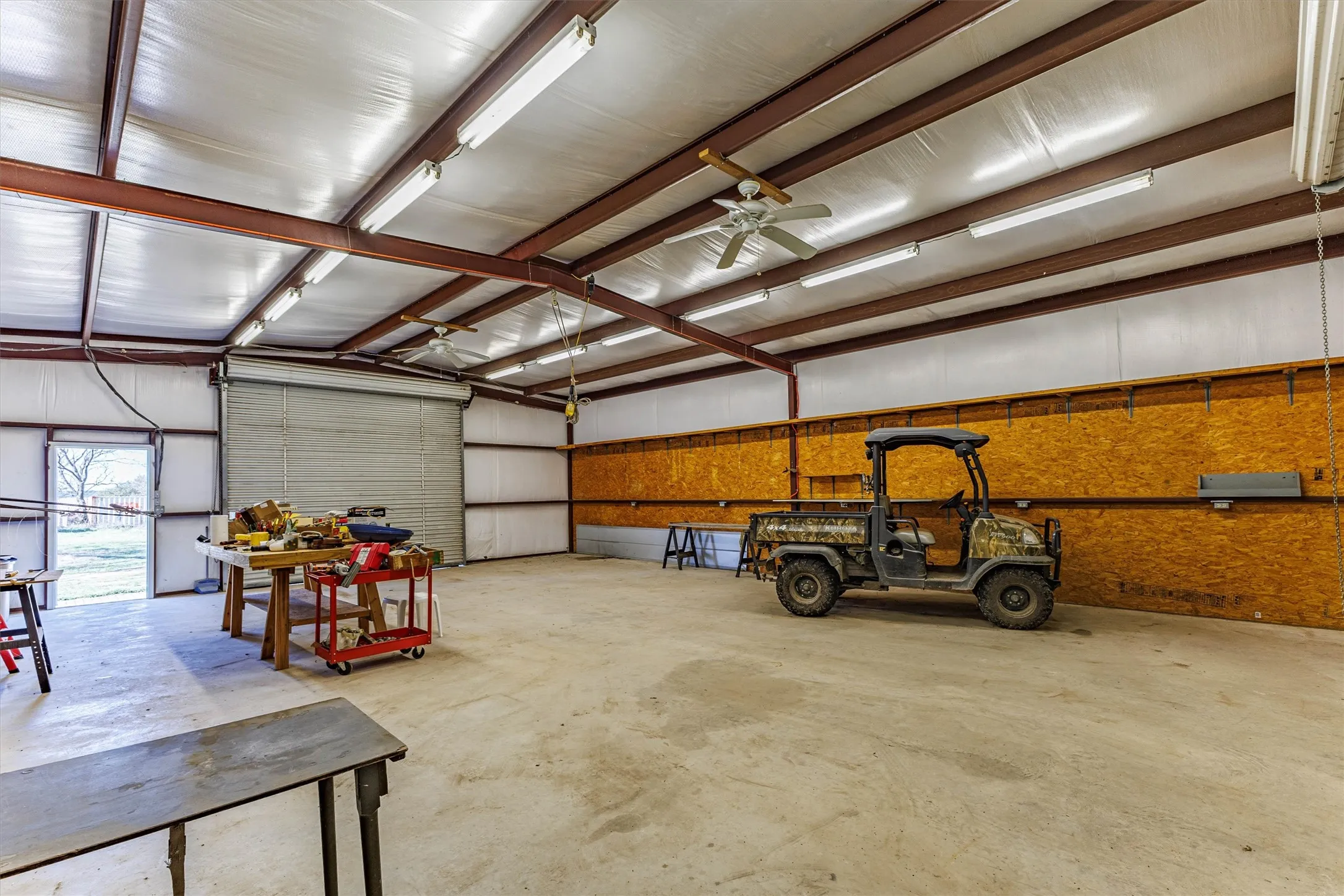 Spacious interior featuring a concrete floor, exposed structural beams, and ample overhead lighting
