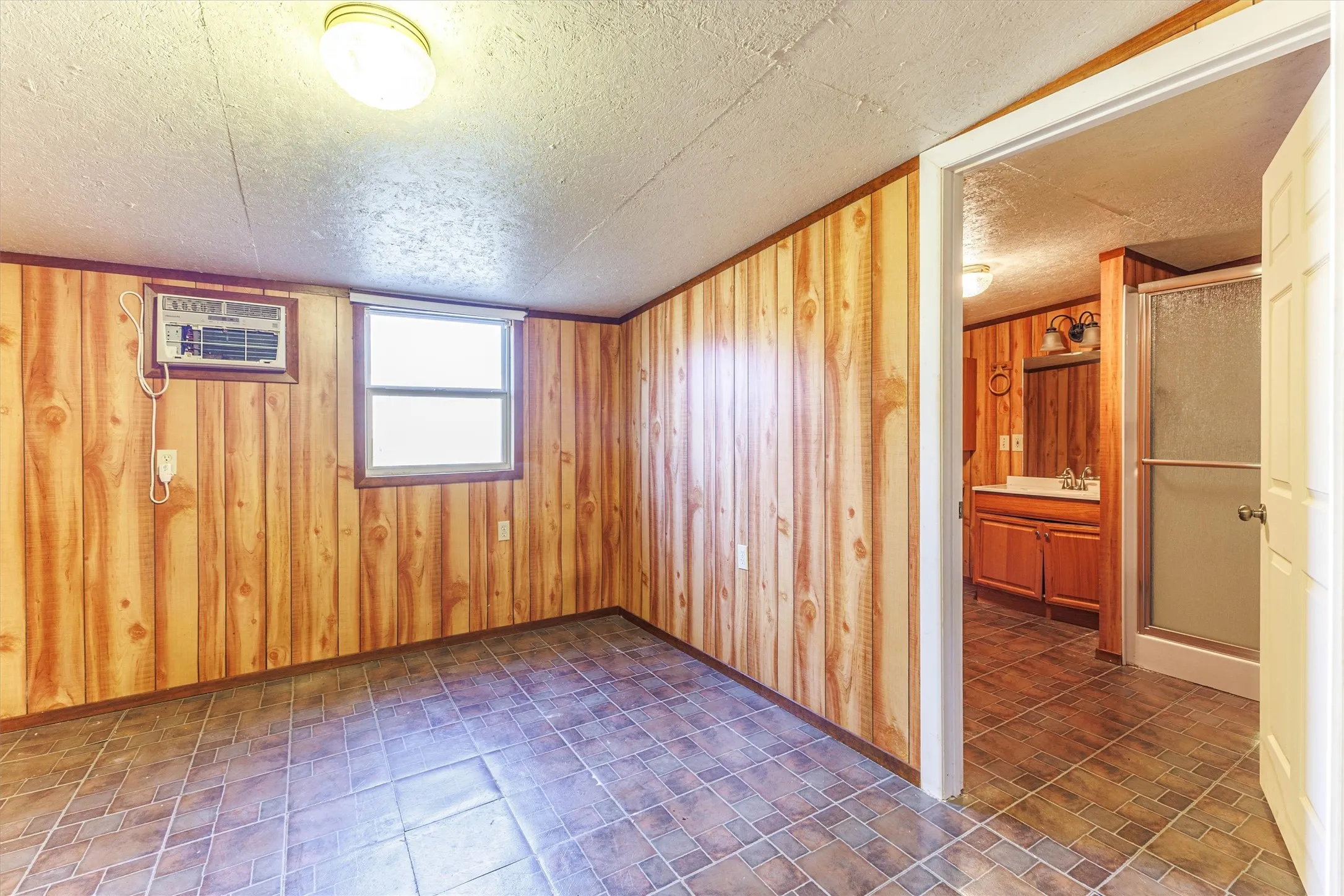 Room featuring wood paneling, tiled flooring, and a window for natural light