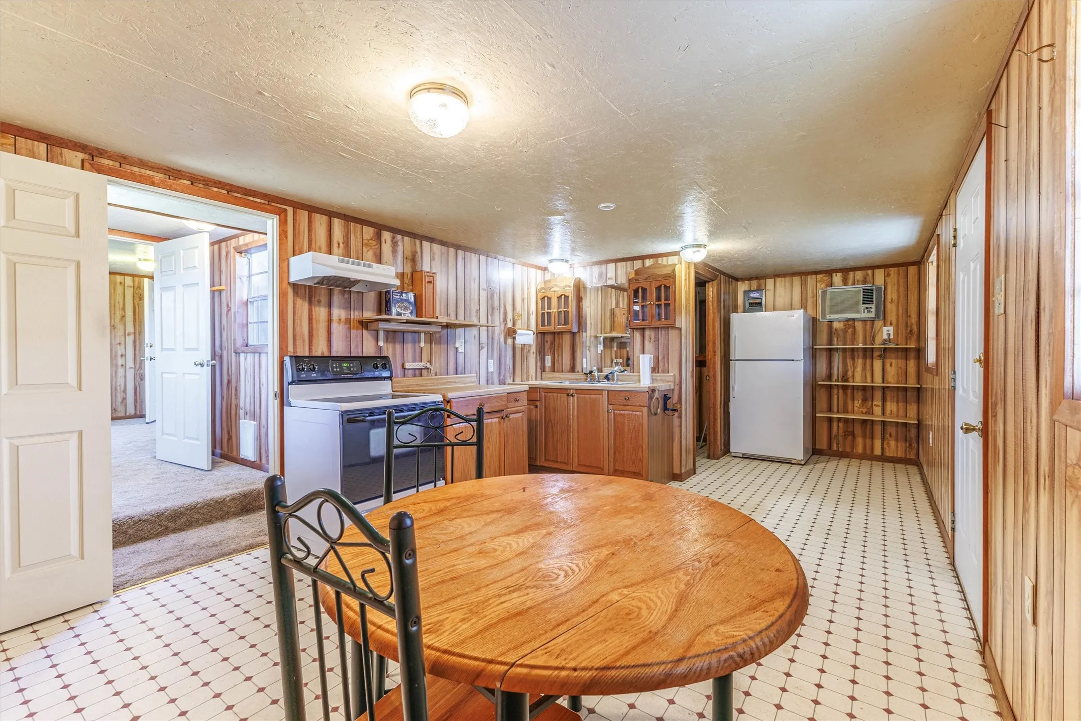 The kitchen features wood paneling, a white electric range, and a white refrigerator