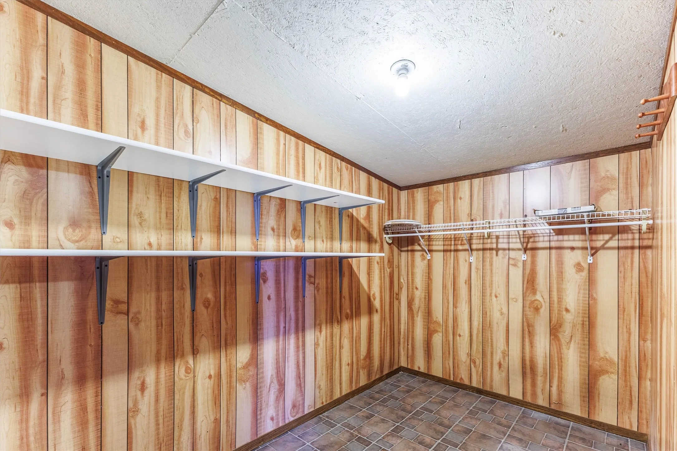 This storage room features wood paneling, a tiled floor, and a textured ceiling