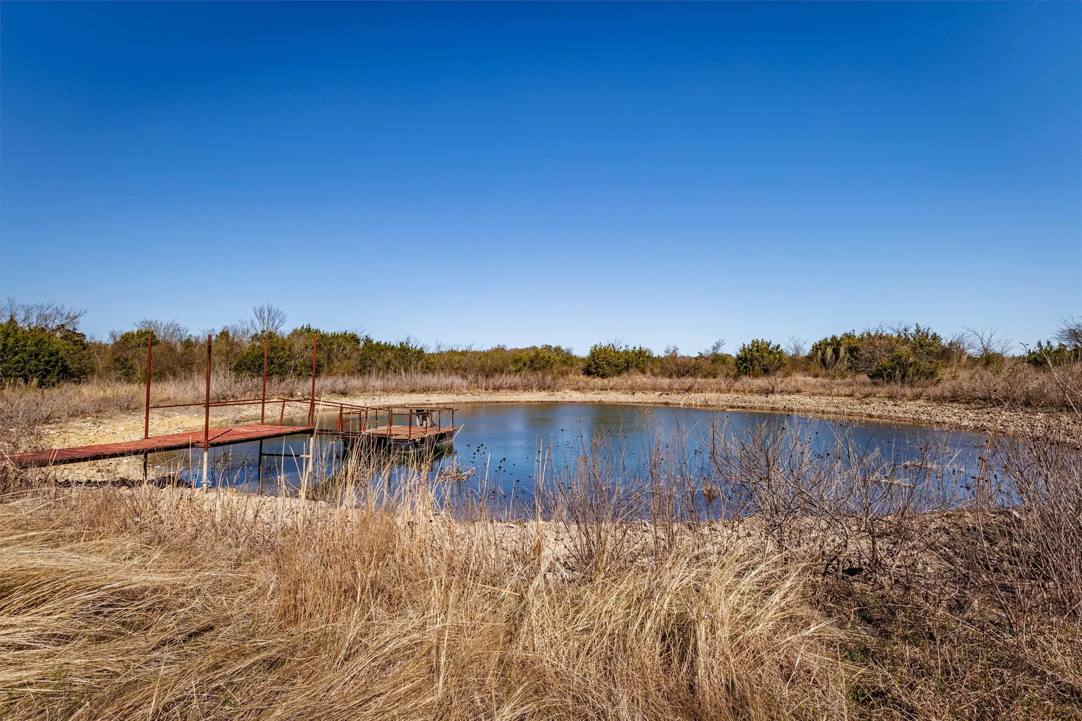 The property includes a pond with a dock, surrounded by natural vegetation