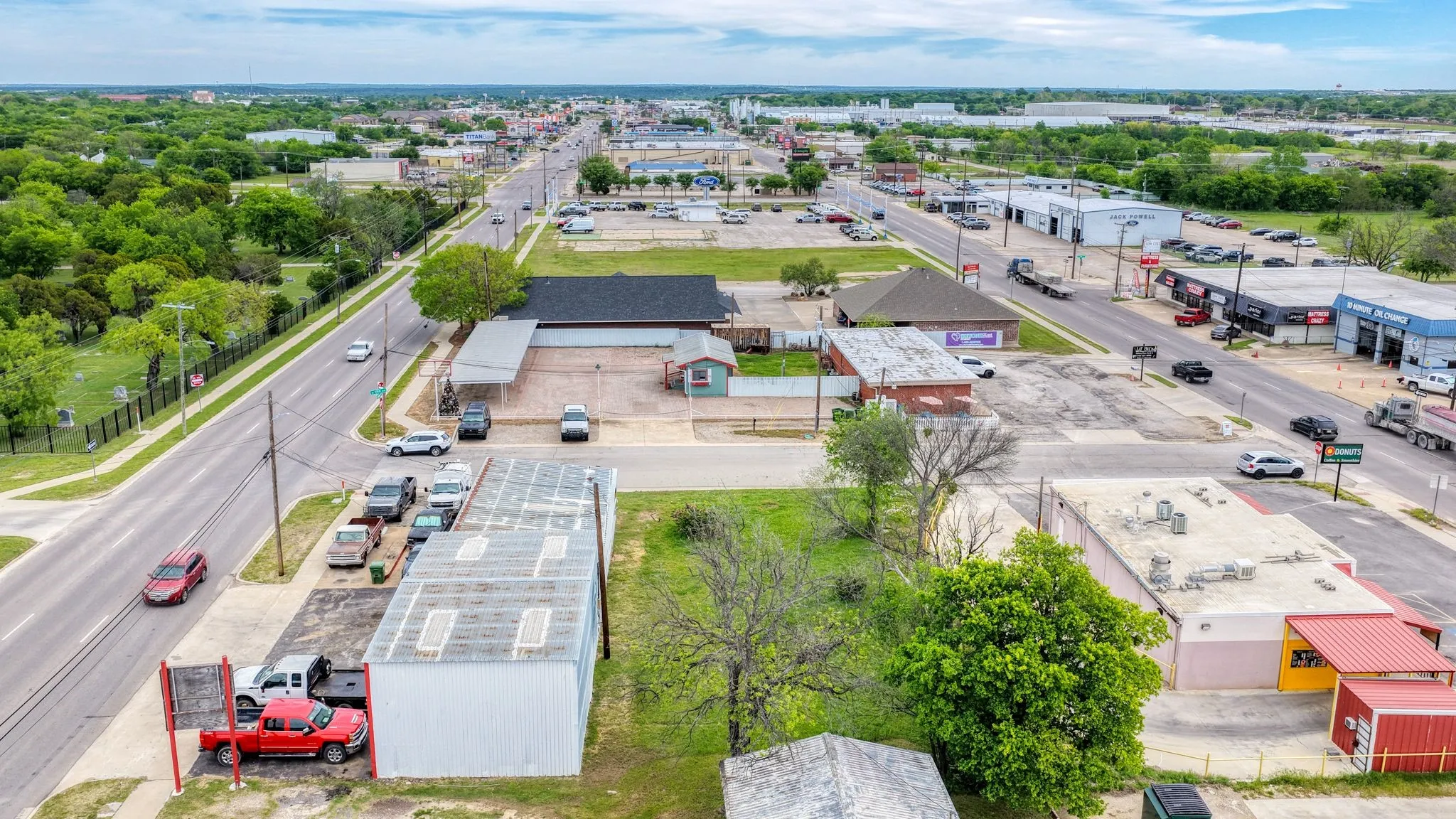 The property is situated on a paved road with surrounding commercial buildings and a green space