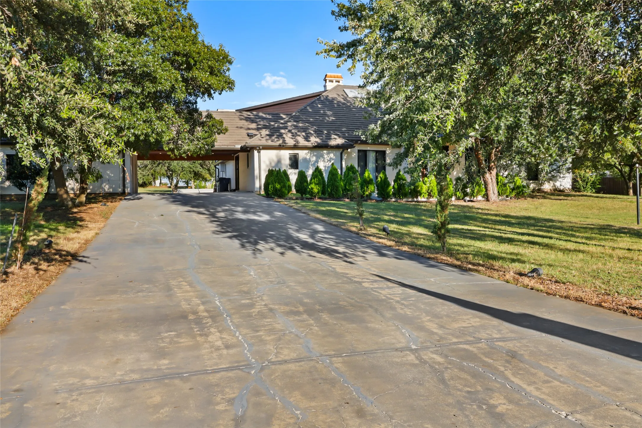 View of front of home with driveway, a front yard, stucco siding, and a carport