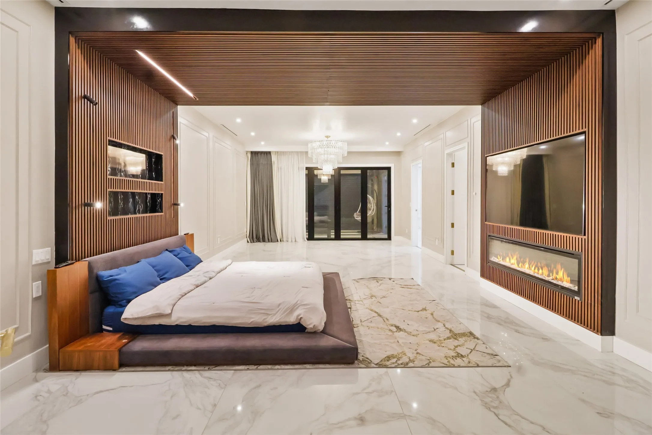 Bedroom featuring marble tiled floors, a glass covered fireplace, a chandelier, and recessed lighting