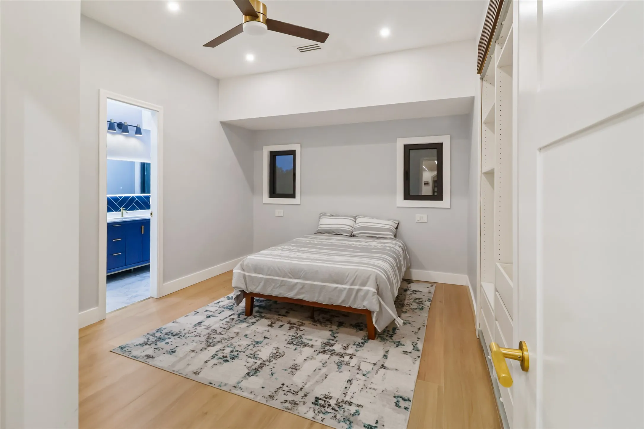 Bedroom with light wood-style floors, recessed lighting, ceiling fan, and ensuite bath