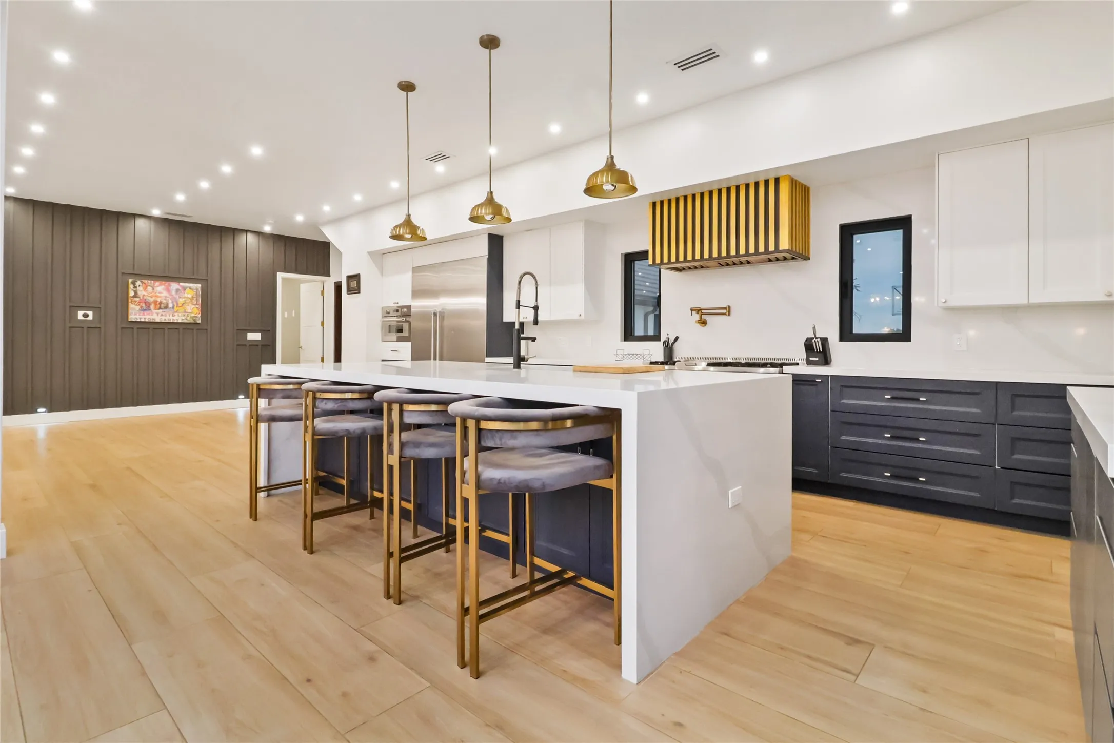 Kitchen with a breakfast bar, a large island, light stone counters, decorative light fixtures, and recessed lighting